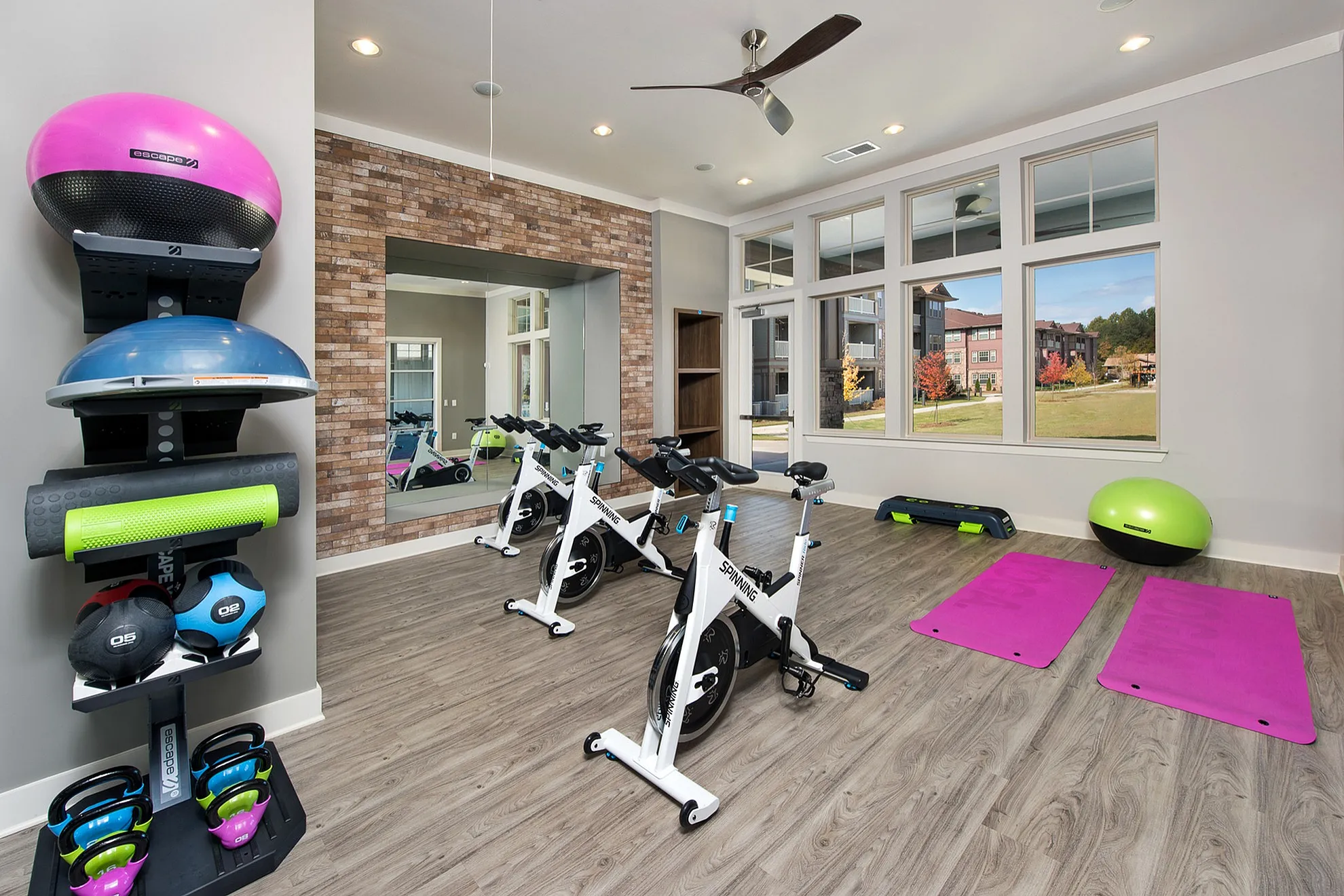 Modern fitness room with yoga mats, spinning bikes, and vibrant exercise equipment, offering a spacious and bright environment.