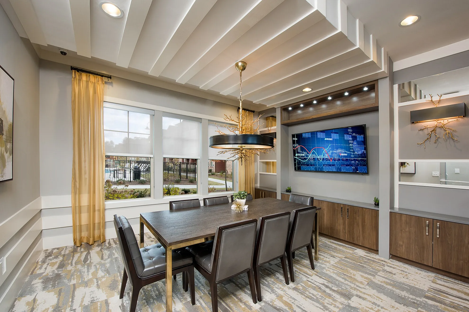 Elegant dining area boasting a modern six-seater table, chic lighting fixture, and large windows with garden views.