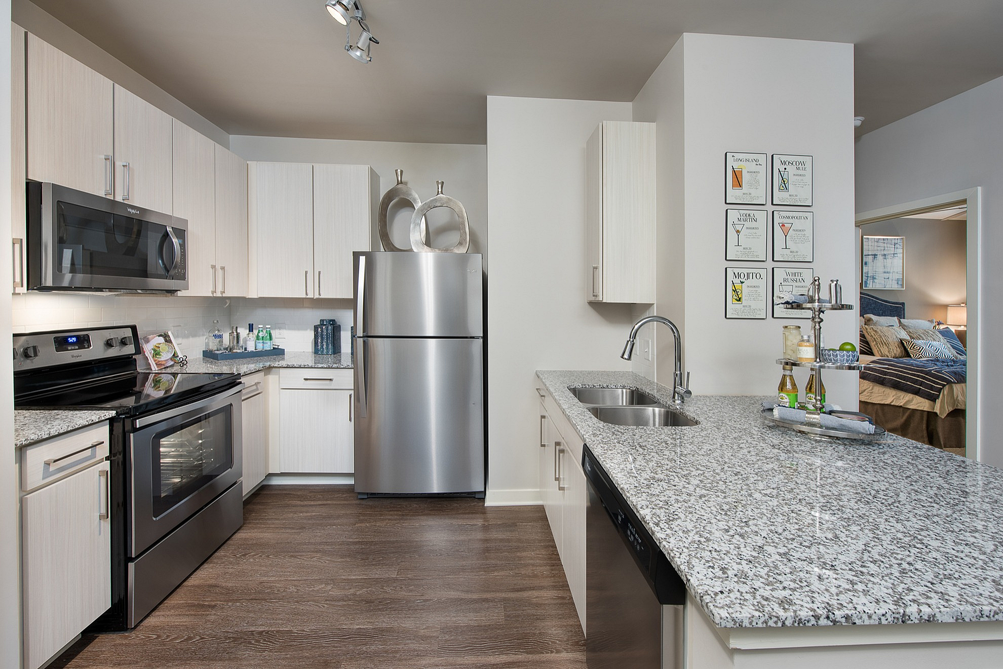 Modern kitchen with sleek stainless steel appliances, granite countertops, and elegant wood flooring, seamlessly connected to a cozy bedroom.