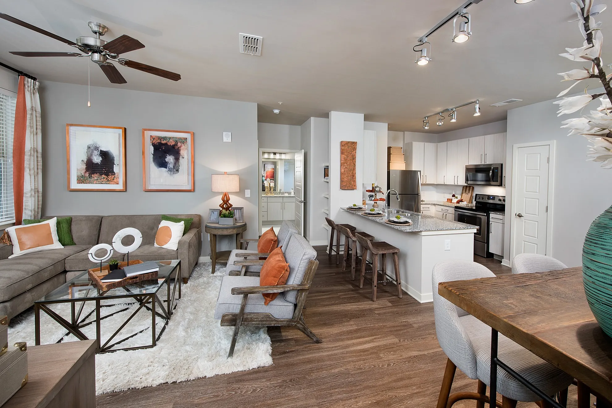 Modern open-concept living room and kitchen with elegant decor, featuring cozy seating, vibrant artwork, and a sleek breakfast bar.