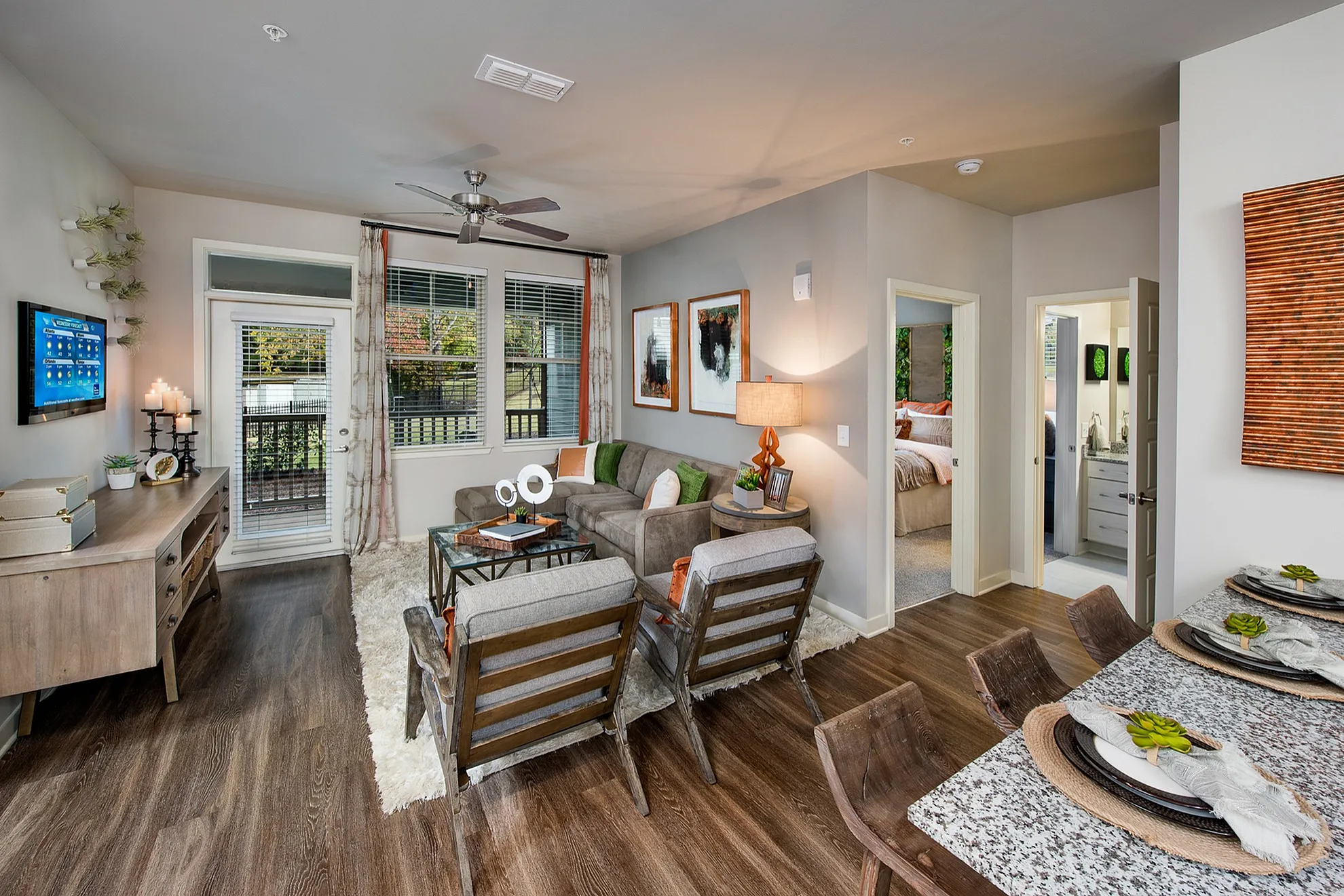 Chic living room with modern decor, featuring a cozy couch, stylish dining area, and a view of the bedroom and balcony.
