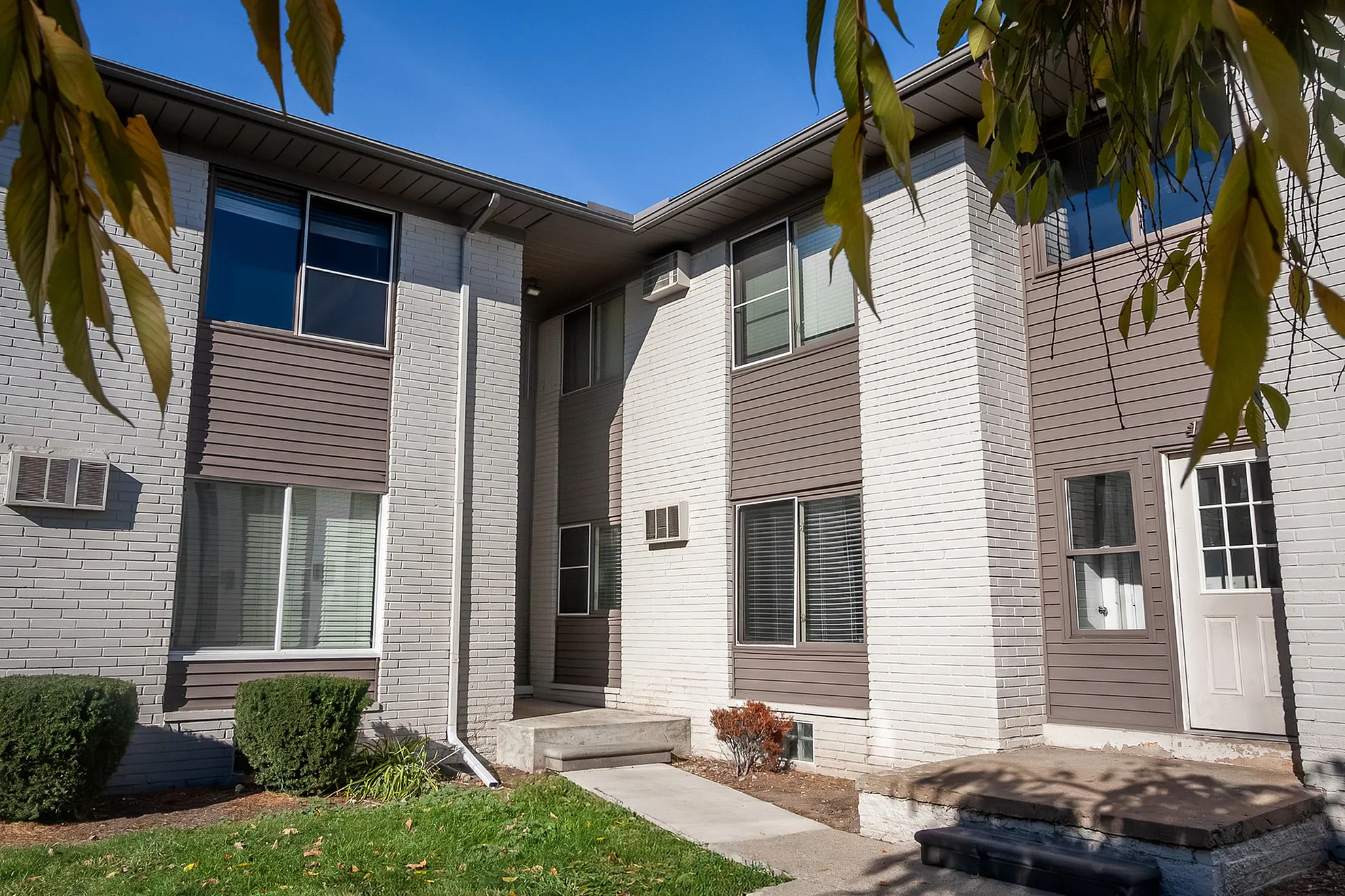 Charming apartment exterior with modern design, showcasing clean lines, large windows, and a welcoming entrance surrounded by lush greenery.