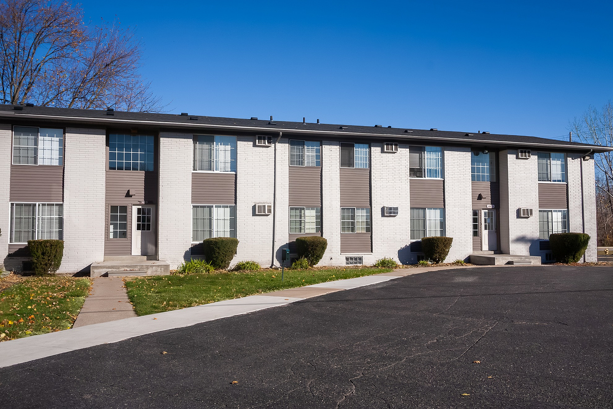 Charming two-story apartment building with modern design, surrounded by lush greenery and a clean, inviting entrance.