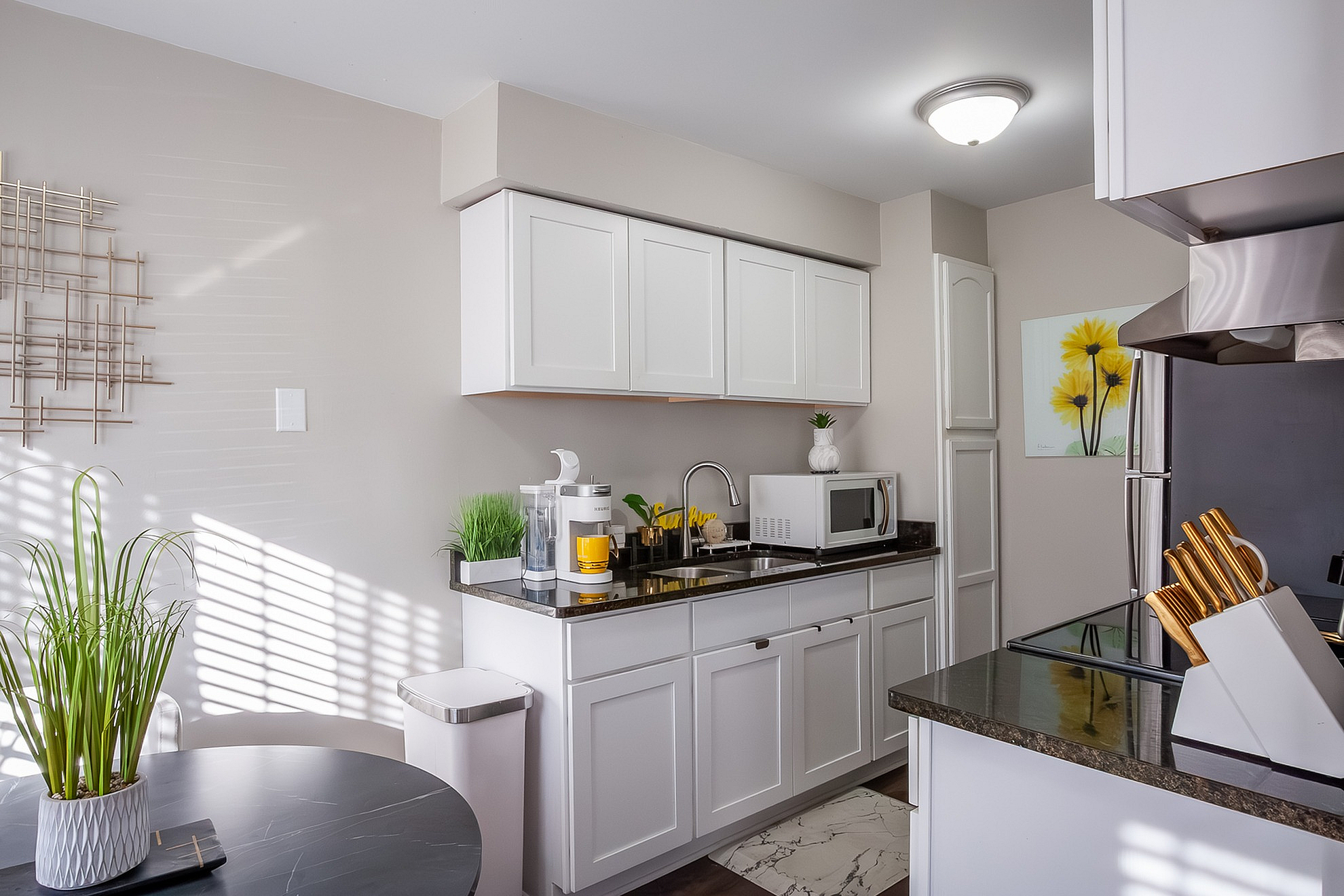 Bright and modern kitchen with sleek white cabinets, stainless steel appliances, and elegant decor touches.