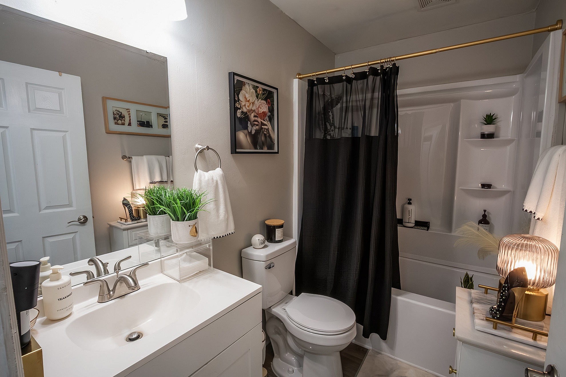 Chic modern bathroom featuring elegant decor, lush greenery accents, and a stylish black shower curtain.