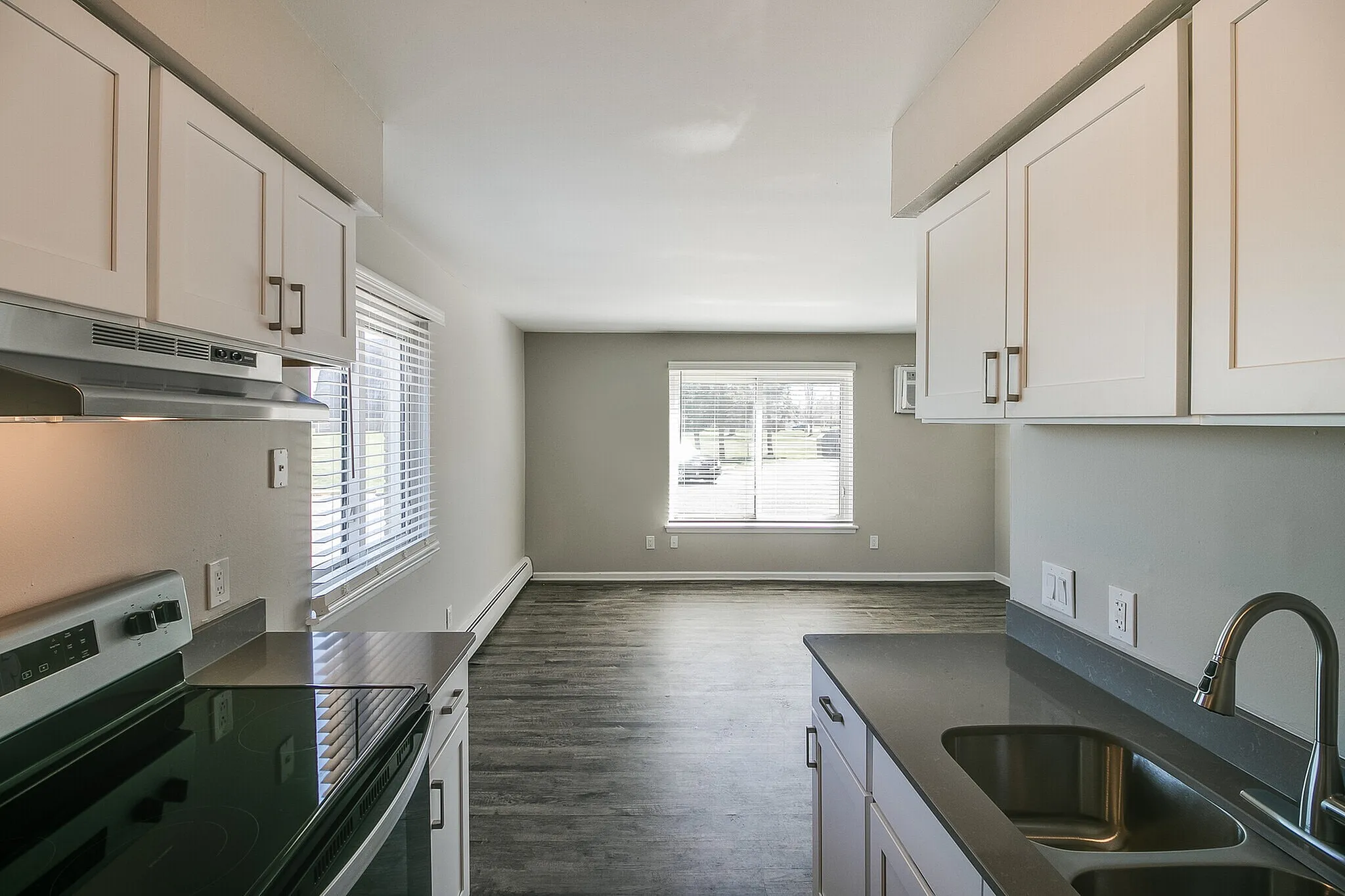 Bright and modern kitchen opening to a spacious living area with elegant flooring and large windows.