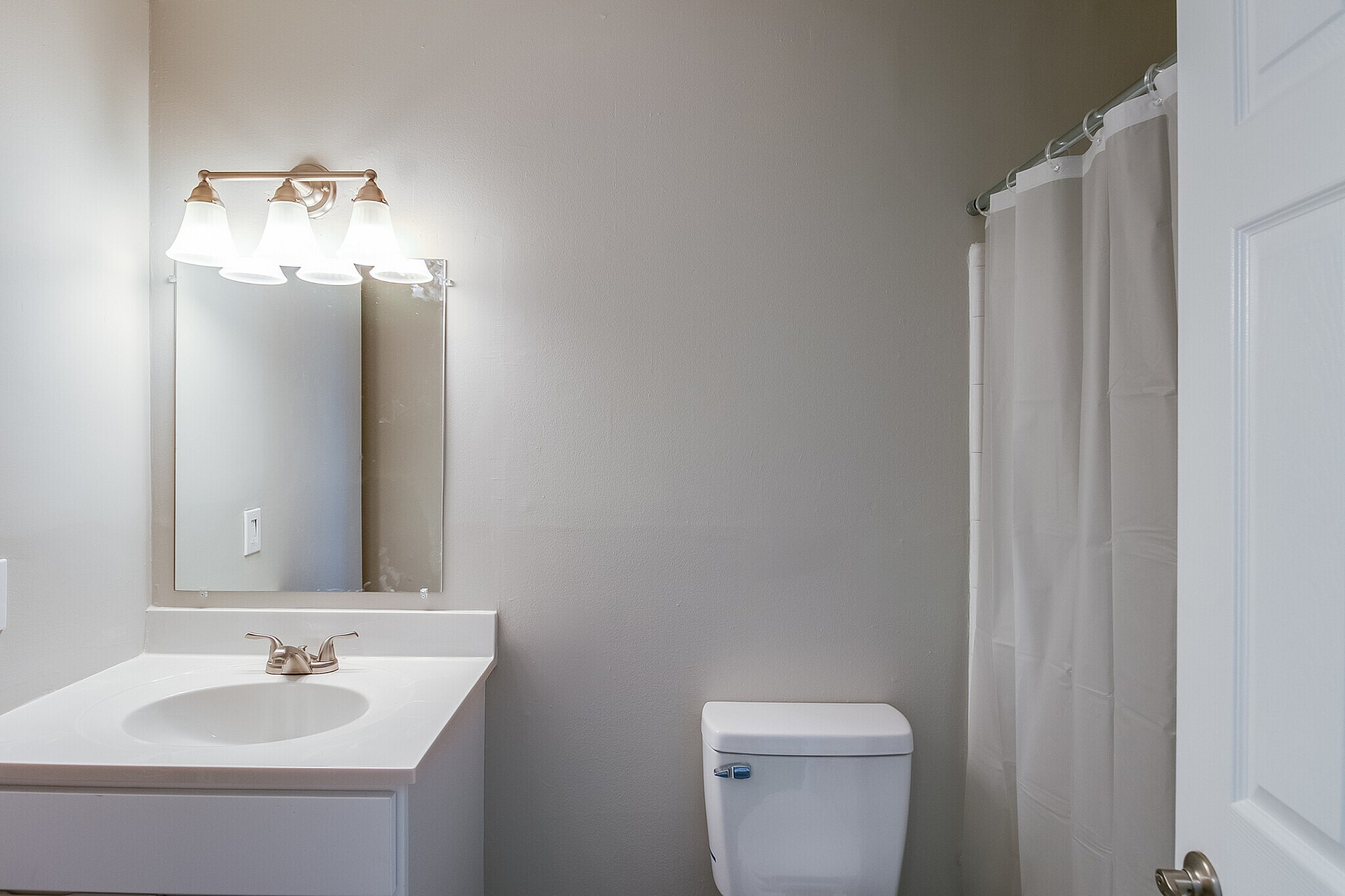 Elegant bathroom showcasing a sleek vanity with modern lighting and a pristine shower curtain.