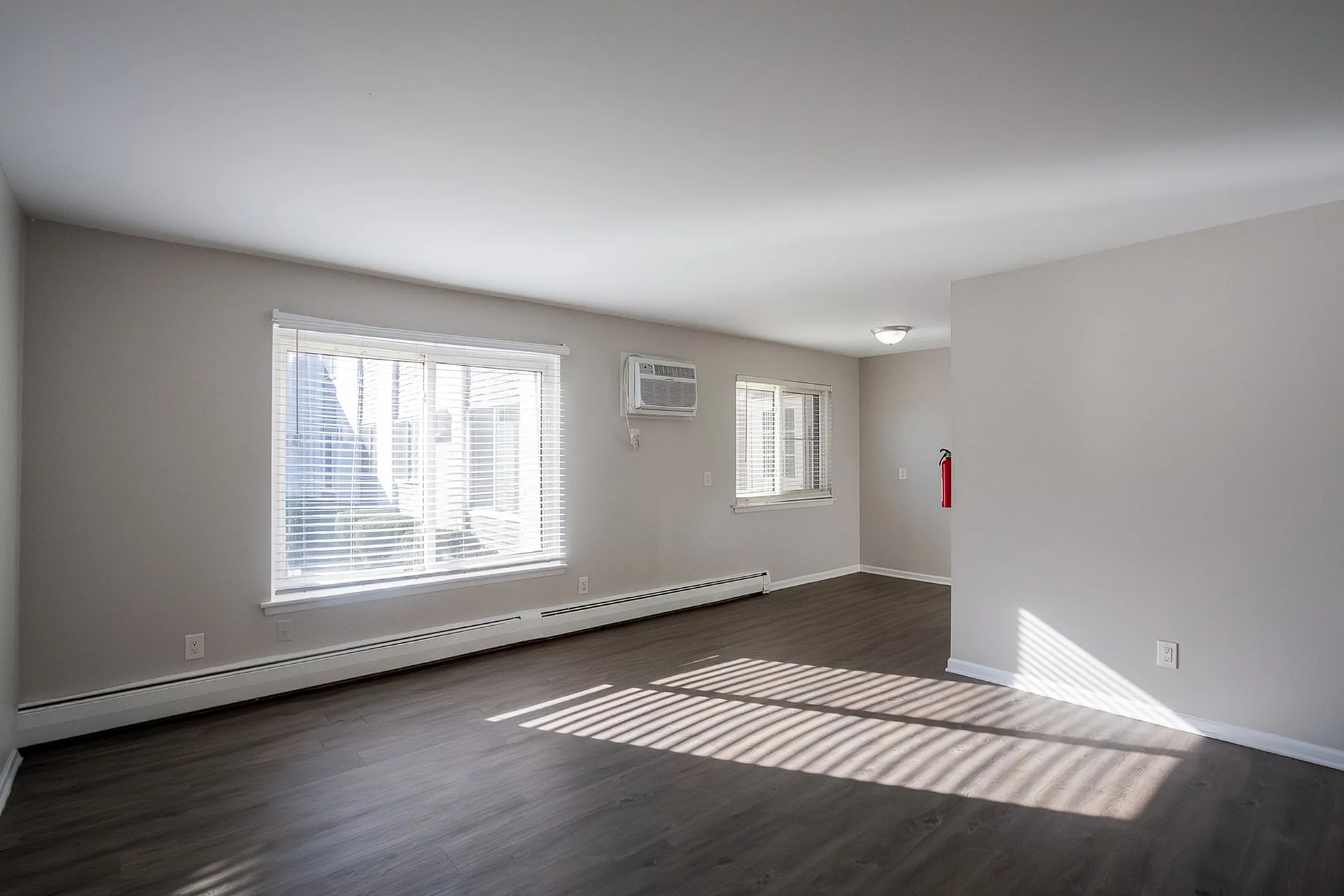 Bright and airy unfurnished living space with large windows, elegant wooden flooring, and modern air conditioning.