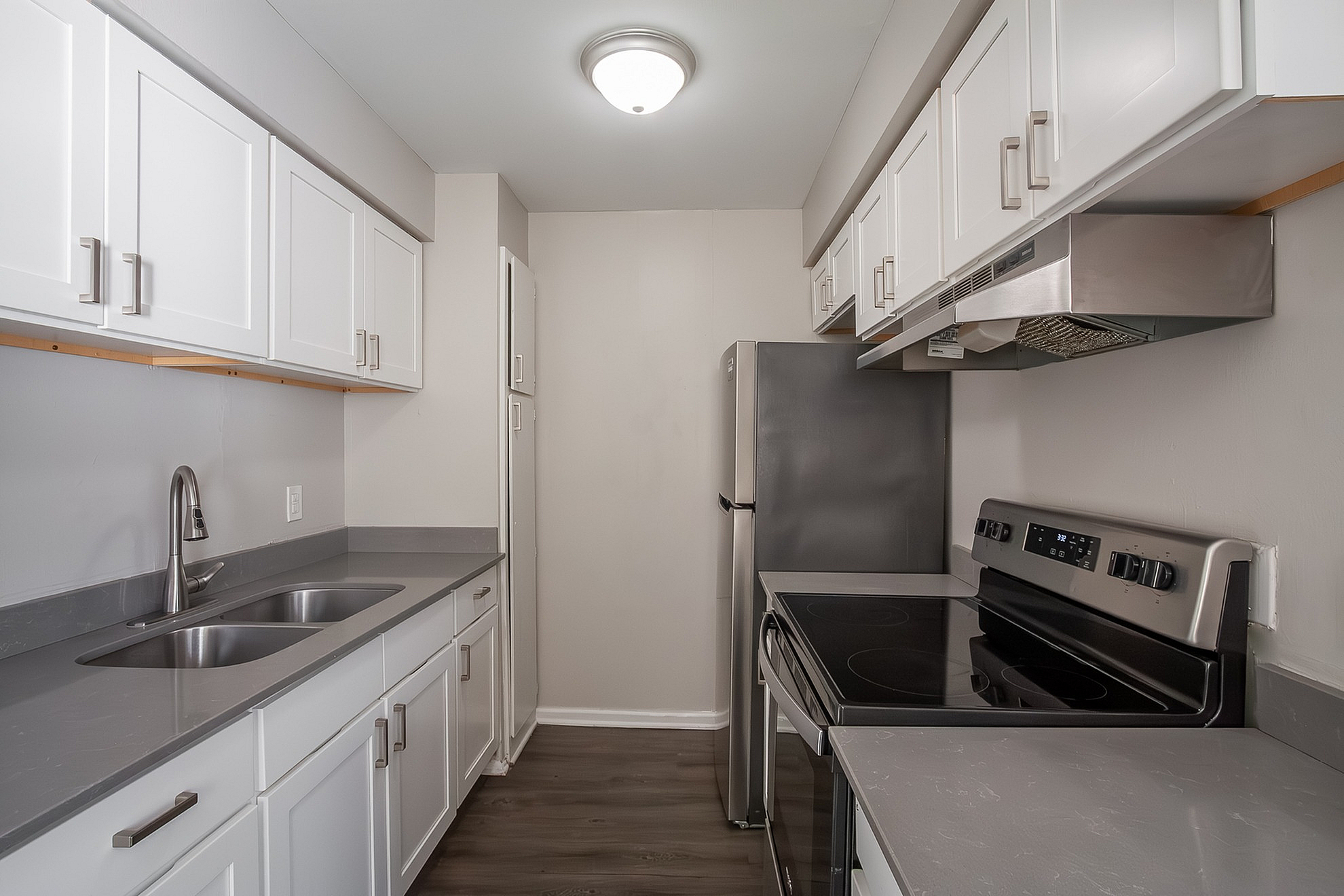 Modern galley kitchen with sleek white cabinetry, stainless steel appliances, and elegant gray countertops.