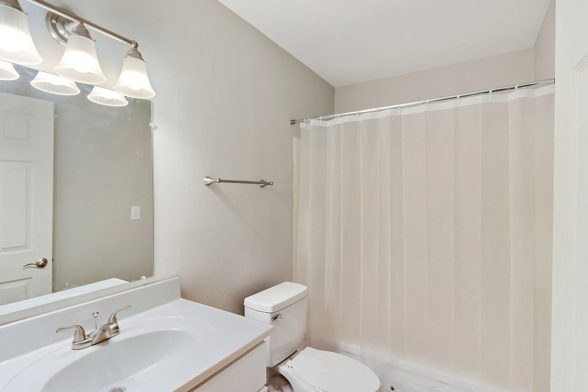 Bright and modern bathroom featuring a sleek vanity, elegant lighting, and a pristine shower curtain.