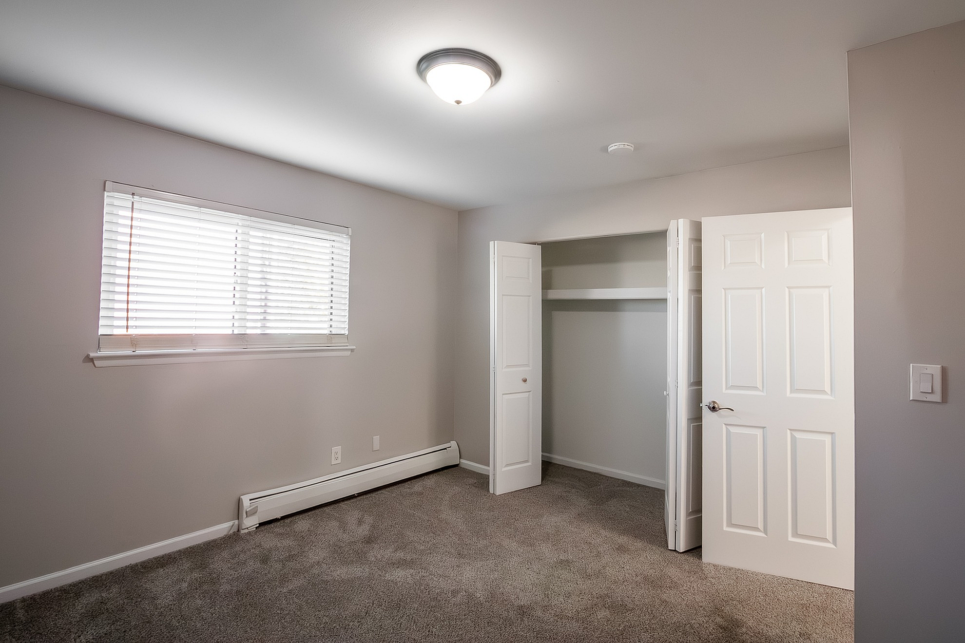Bright, spacious bedroom with plush carpet, built-in closet, and large window for abundant natural light.