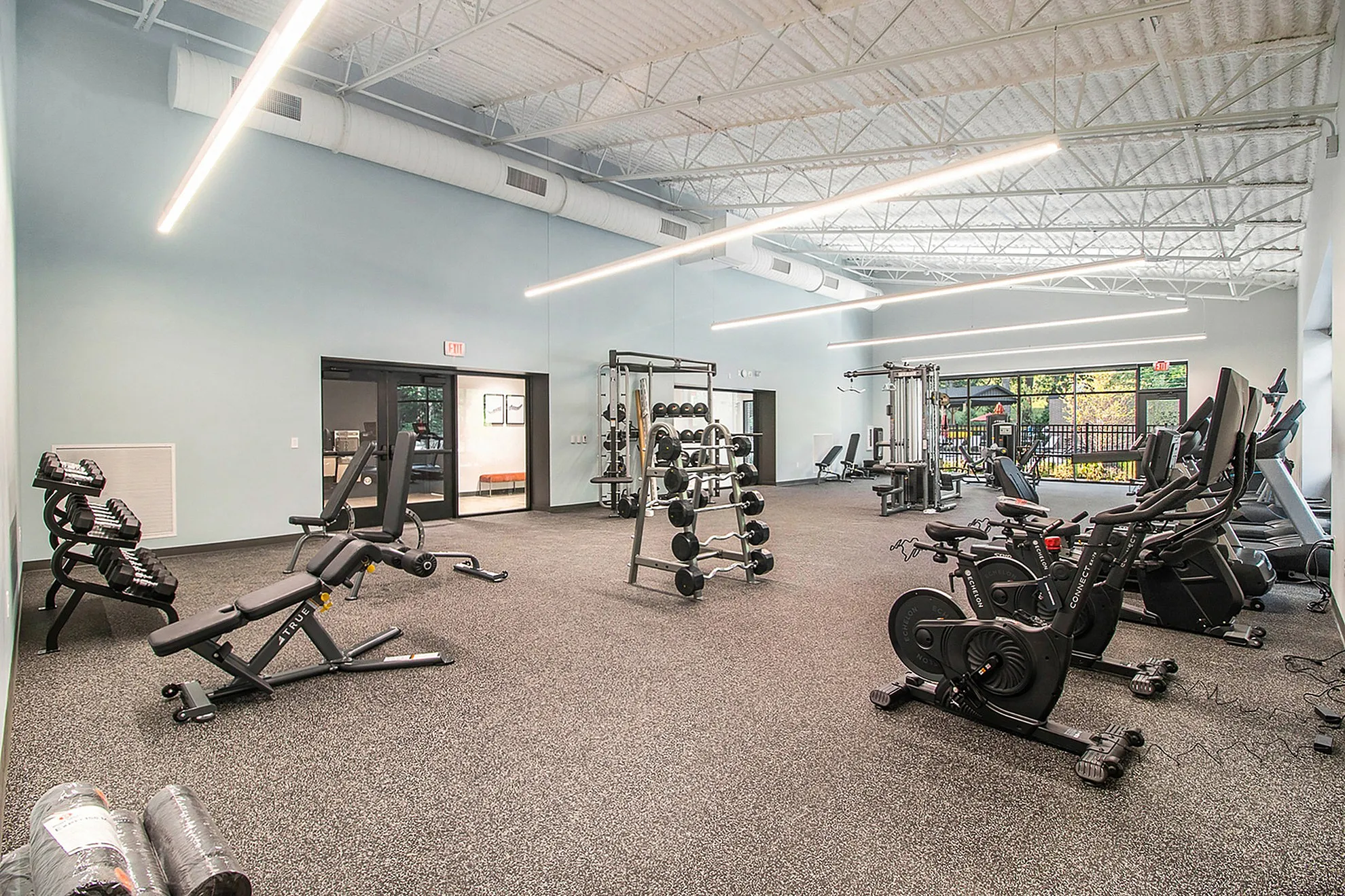 Modern gym facility featuring state-of-the-art equipment, ample lighting, and spacious workout areas with external views.