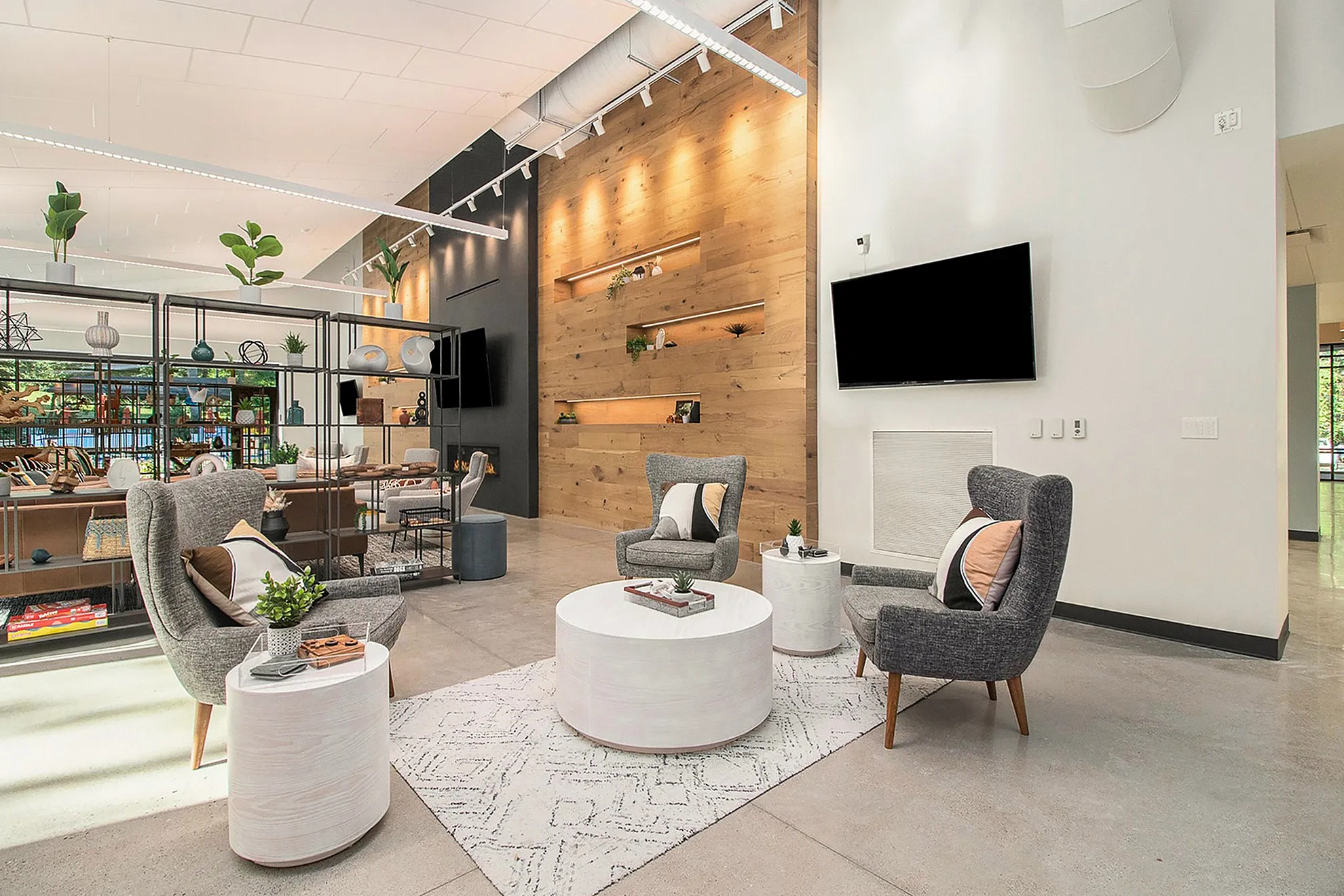 Modern living space with chic decor featuring gray chairs, wooden accents, and vibrant greenery.