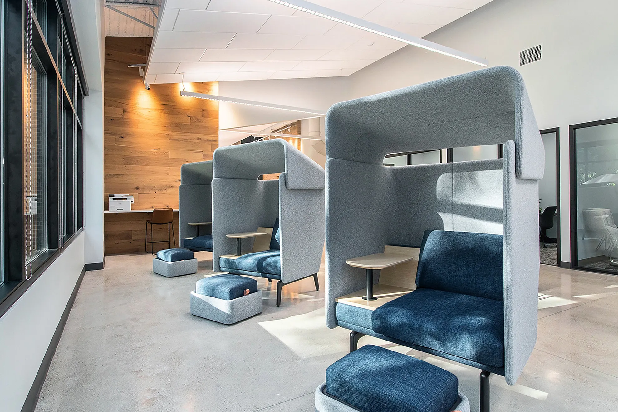 Contemporary office space featuring modern pod seating with plush cushions and wood accents, perfect for a creative work environment.