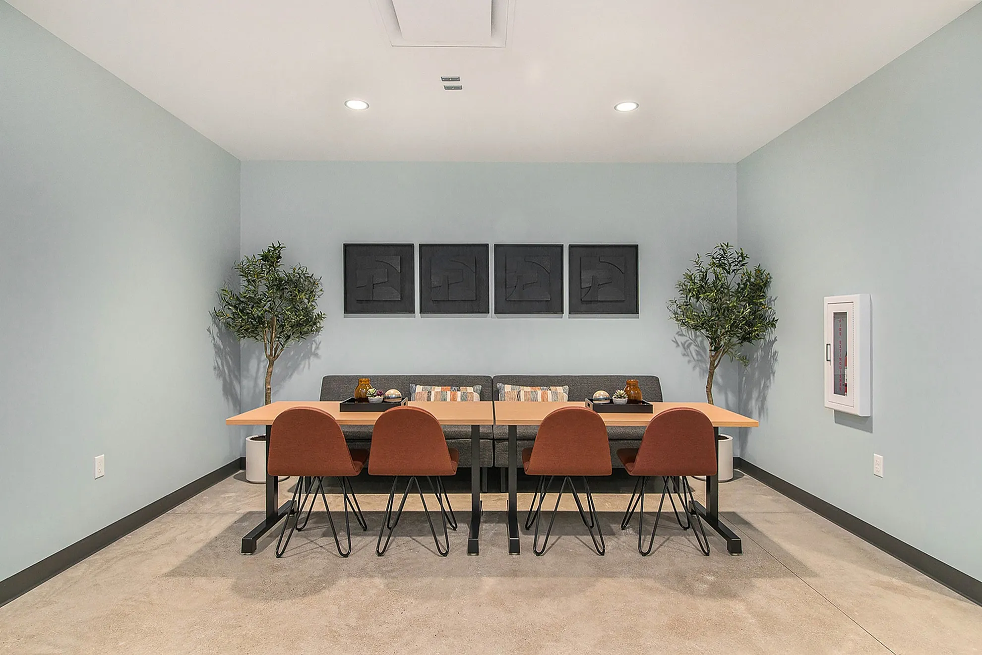 Contemporary dining area with a sleek wooden table, comfortable seating for six, elegant decor, and stylish artwork on a serene blue wall.