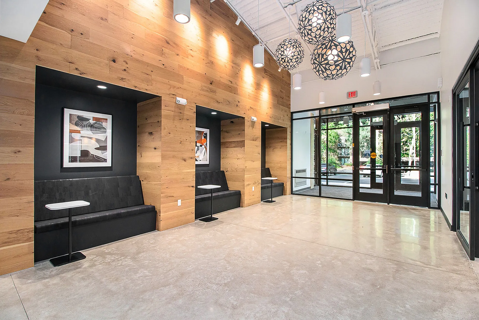 Contemporary lobby with sleek seating alcoves and stylish wood paneling, illuminated by modern hanging lights.