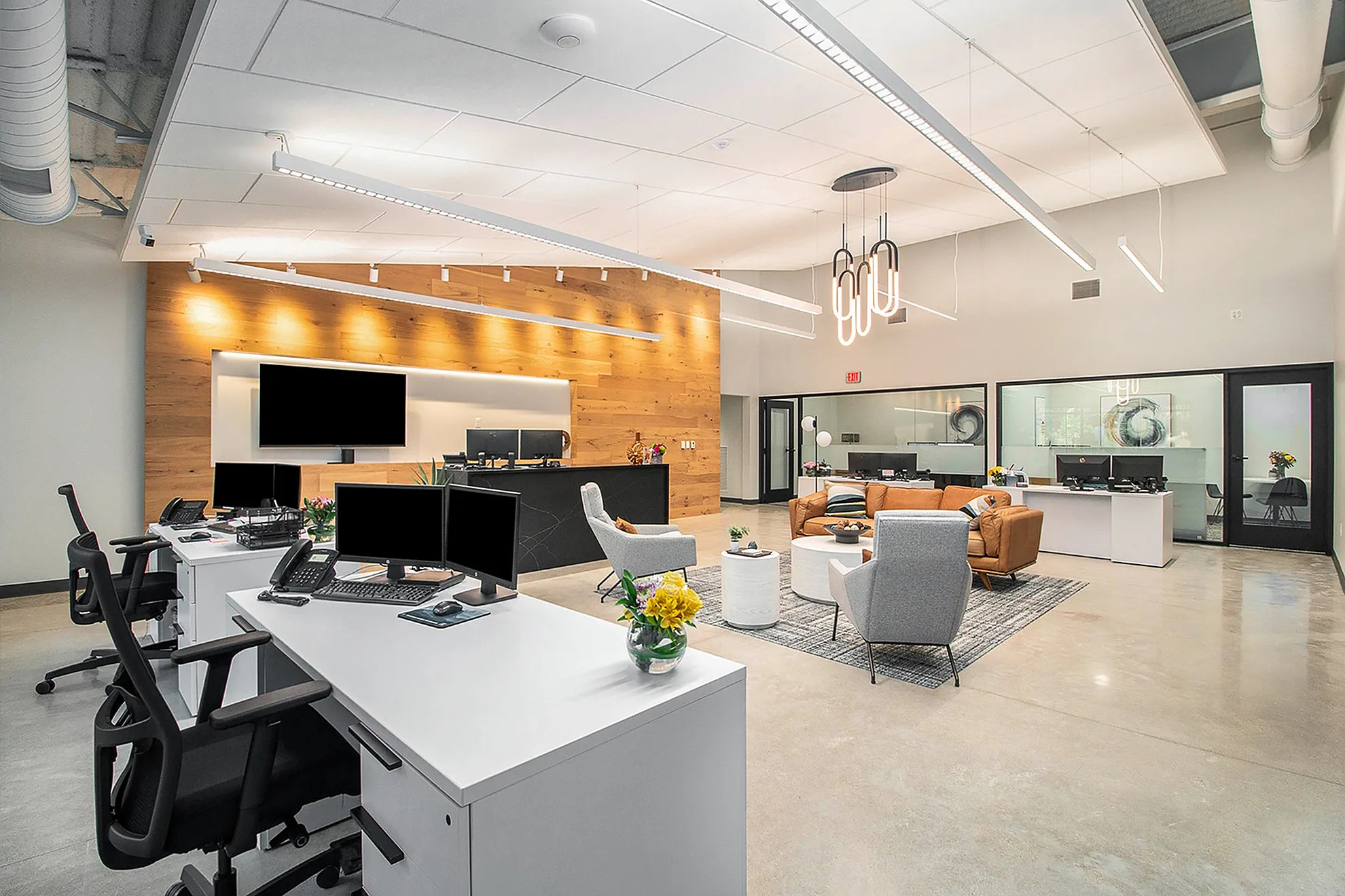 Modern open-plan office space with sleek workstations, comfortable seating area, and stylish lighting fixtures.