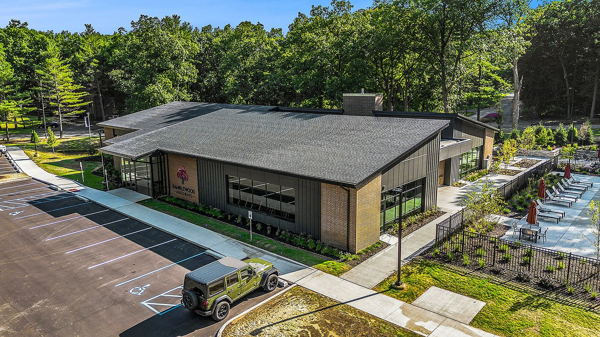 Modern apartment complex surrounded by lush greenery, featuring a sleek exterior and inviting outdoor pool area.