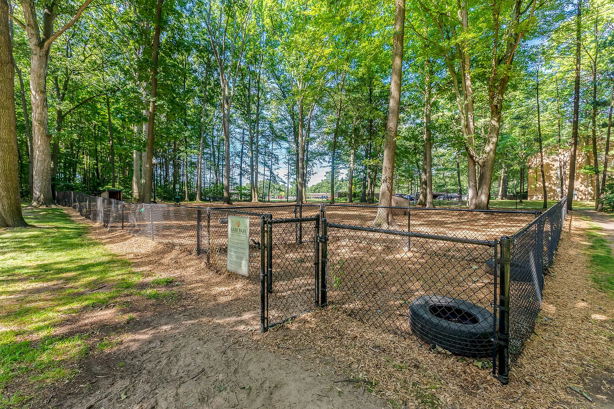 Inviting dog park nestled in a serene wooded area, surrounded by a secure fence with ample space for pets to play and explore.