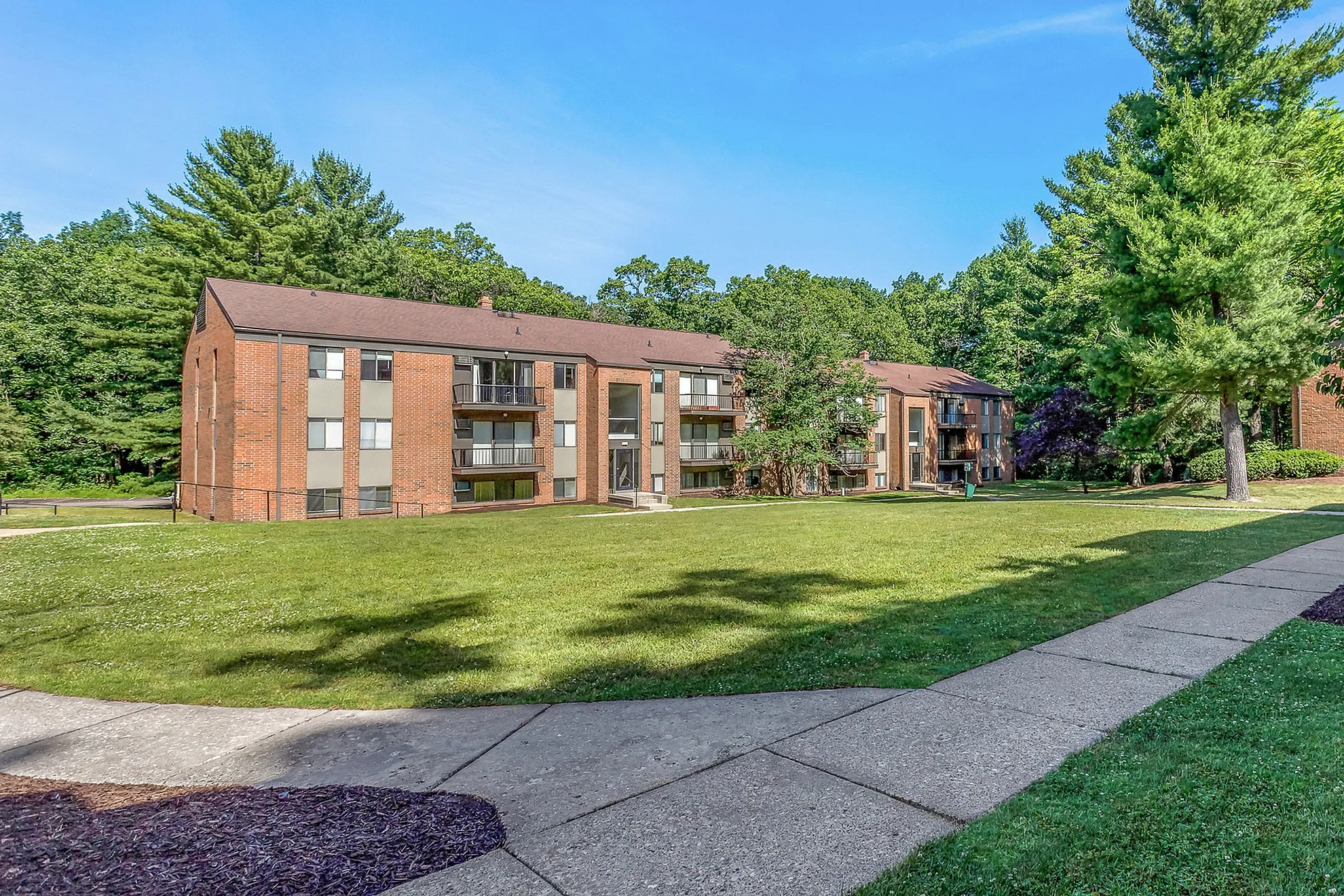 Charming brick apartment building set amidst lush greenery, offering spacious living with scenic views and vibrant community spaces.