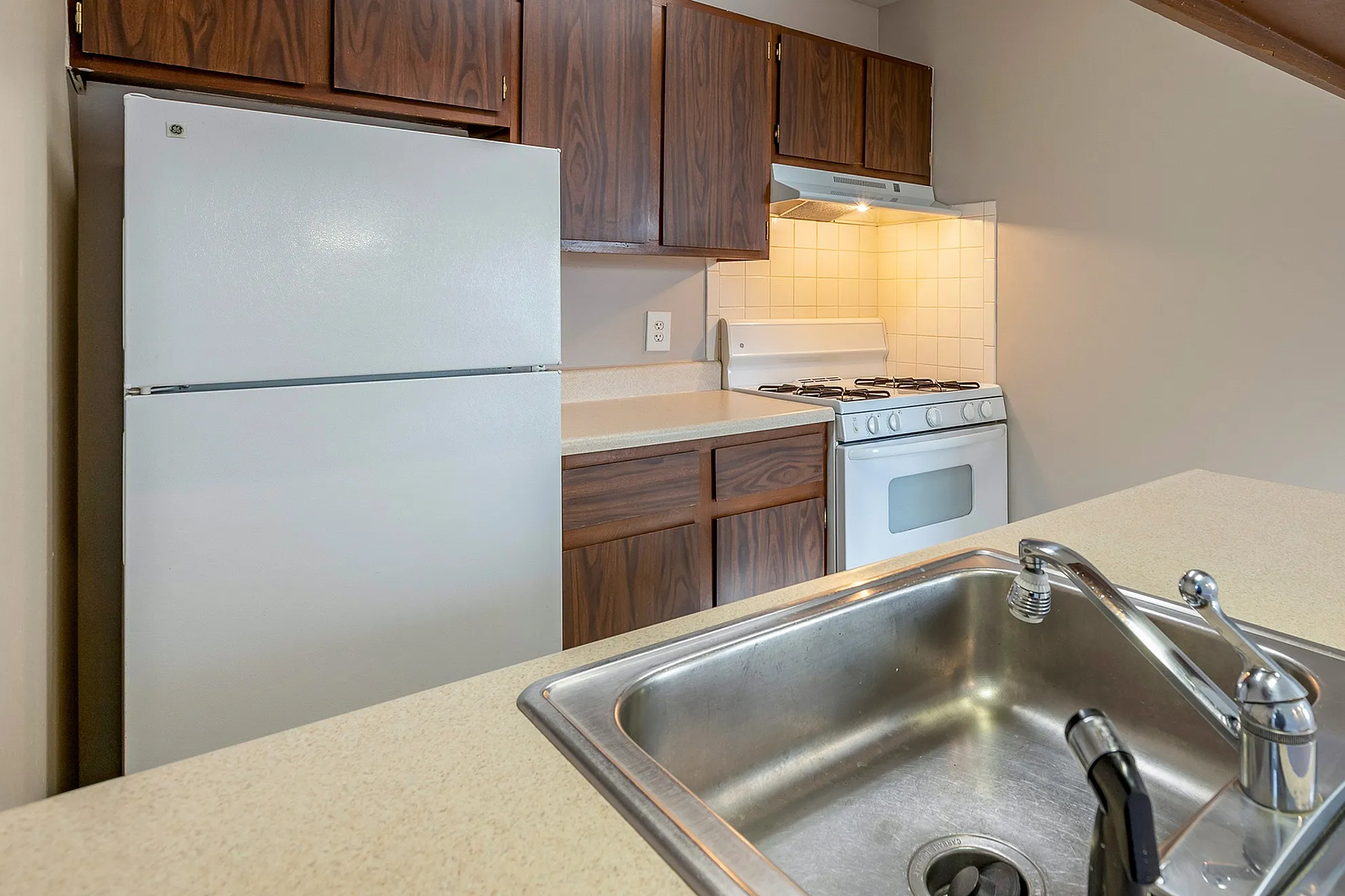 Chic kitchen with wood cabinetry, modern white appliances, and sleek countertop featuring a built-in sink, ideal for culinary enthusiasts.