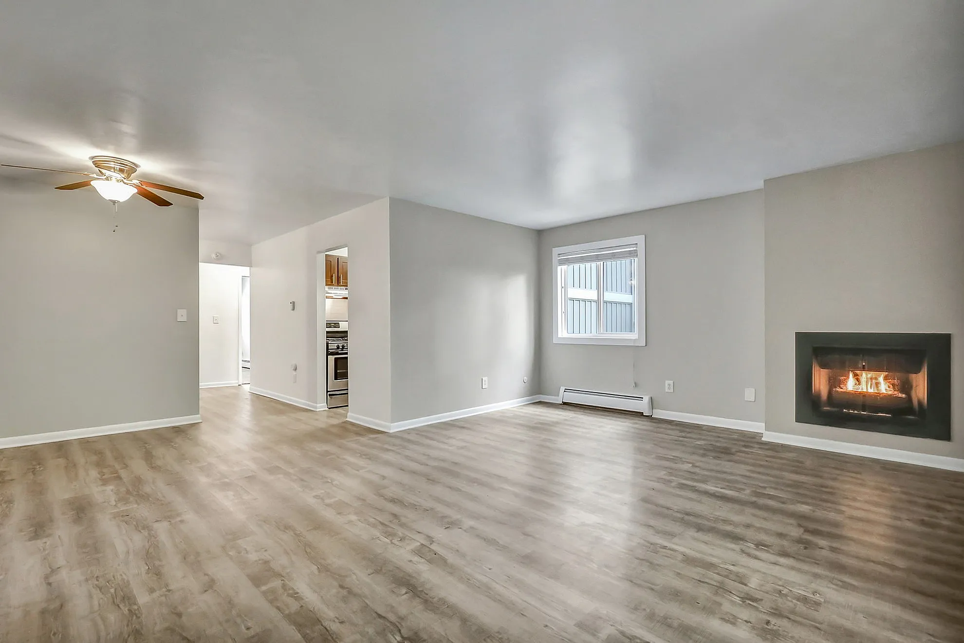 Bright and spacious living area featuring elegant hardwood floors, a cozy fireplace, and a modern ceiling fan.
