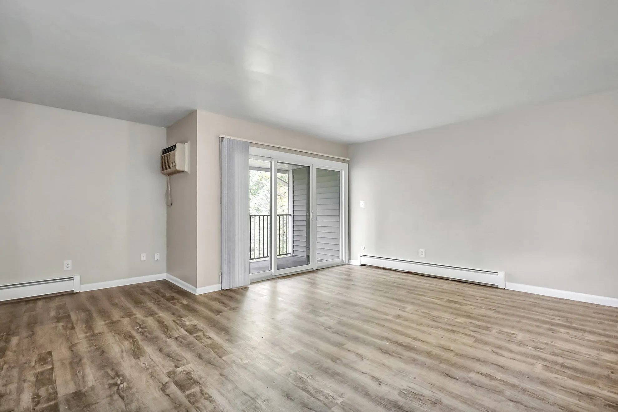 Bright and airy living room with sleek hardwood floors, sliding glass doors leading to a private balcony, and a modern minimalist design.