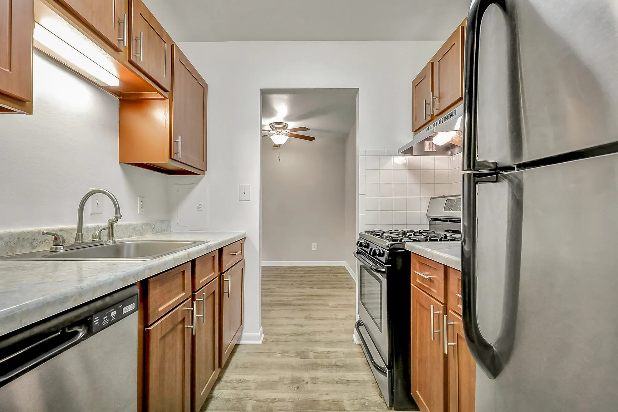 Sleek modern kitchen featuring stainless steel appliances, elegant wood cabinetry, and rich laminate flooring.
