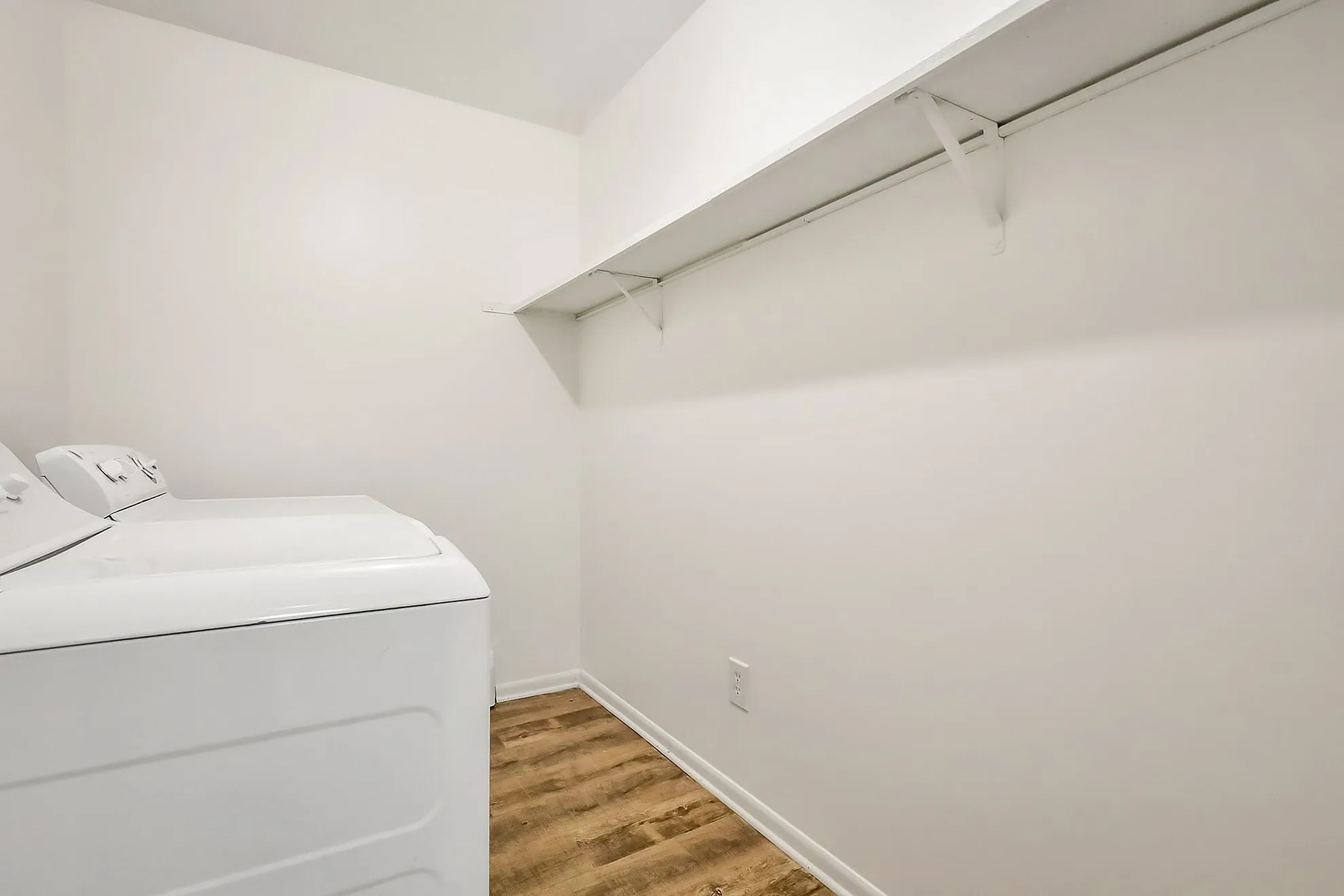 Spacious laundry room with modern washer and dryer, featuring sleek shelving and stylish flooring.