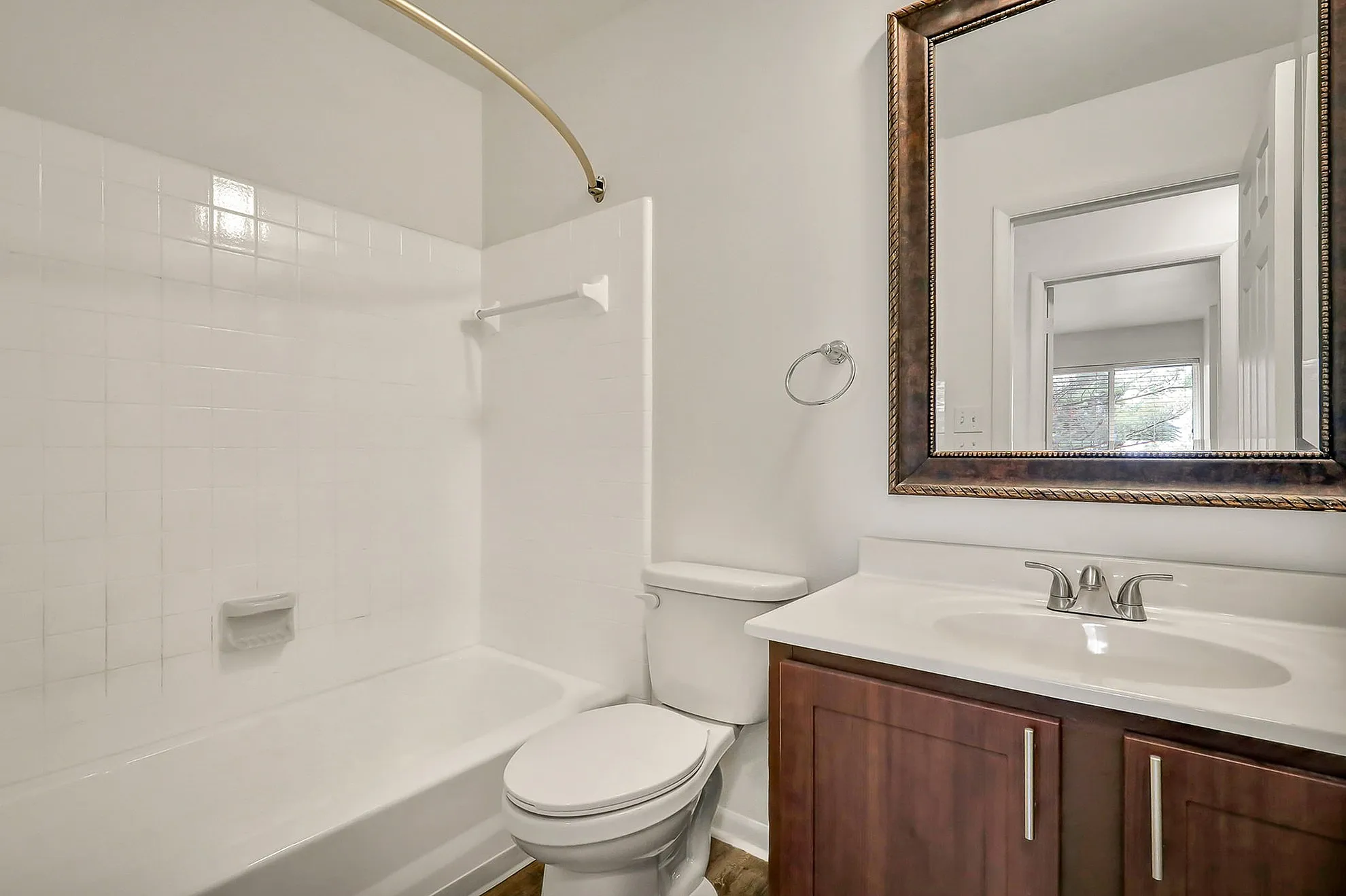 Elegant bathroom featuring a classic white bathtub, modern vanity with sleek fixtures, and a stylish framed mirror.