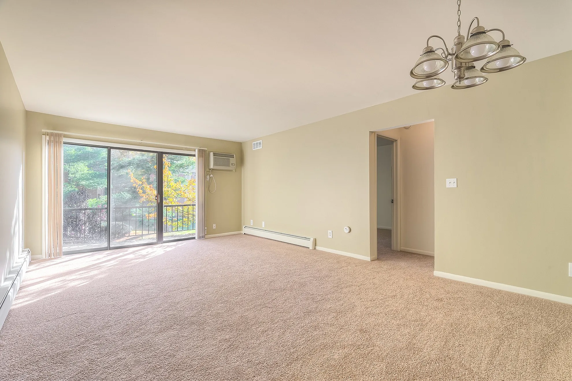 Bright and airy living room featuring large windows with scenic views, plush carpeting, and elegant light fixtures.