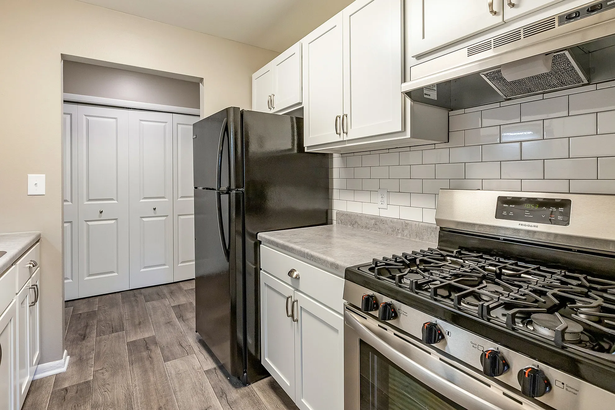 Modern kitchen featuring sleek black appliances, elegant white cabinetry, and stylish subway tile backsplash.
