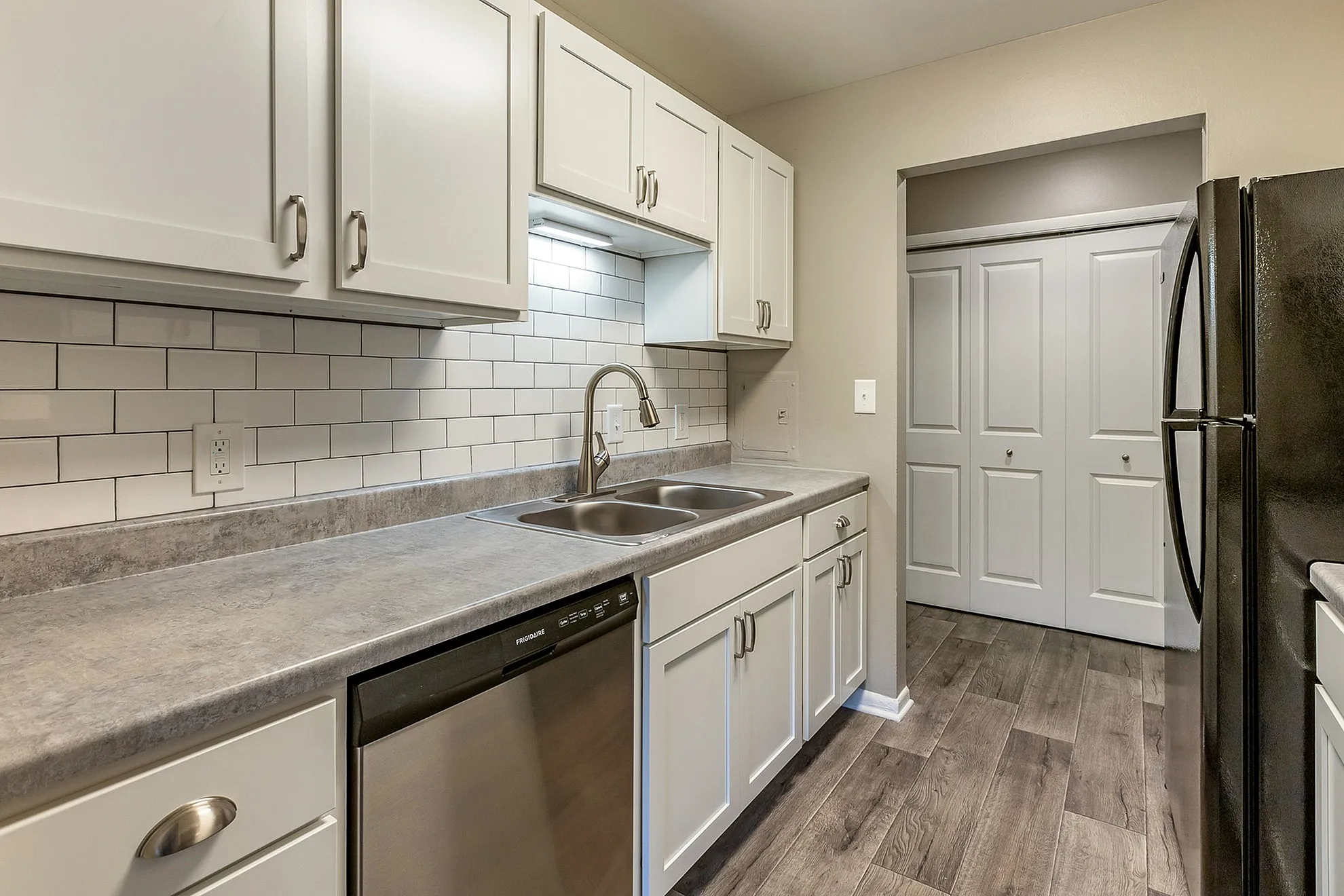 Modern kitchen with elegant white cabinetry, sleek stainless steel appliances, and stylish subway tile backsplash.