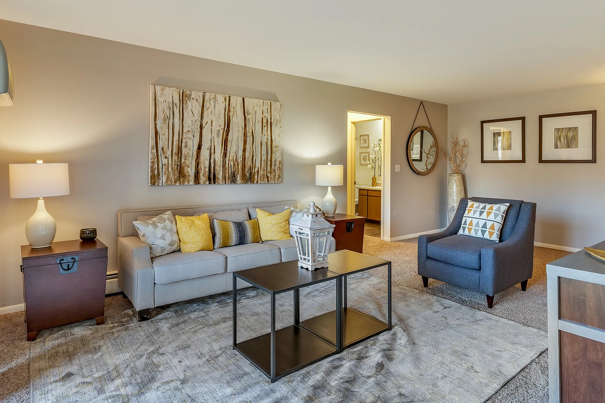Inviting living room with elegant decor, featuring a plush gray sofa, modern armchair, vibrant accent pillows, and warm ambient lighting.