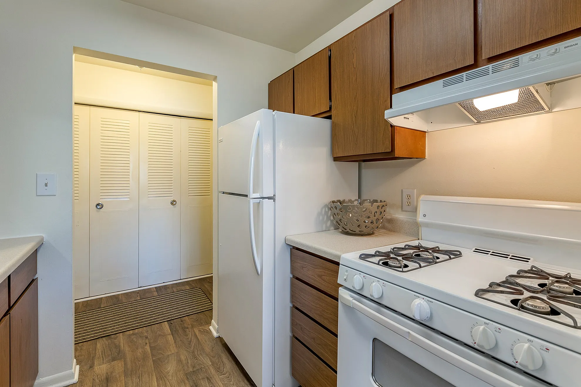 Charming kitchen with sleek white appliances, warm wooden cabinets, and stylish flooring, perfect for modern living.