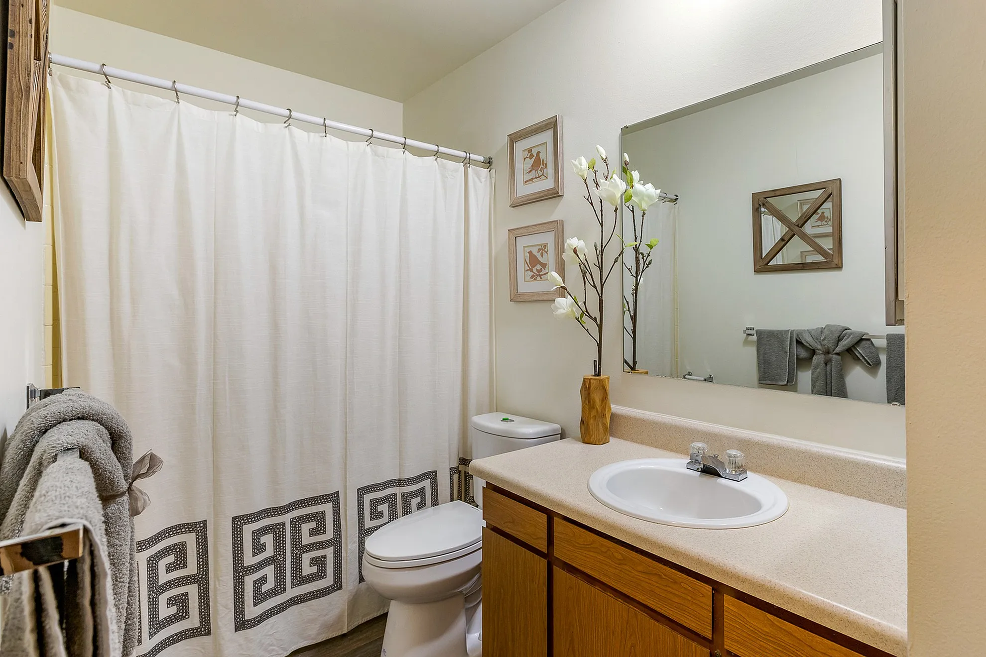Elegant bathroom with a modern vanity, floral decor, and stylish shower curtain, exuding a cozy and inviting atmosphere.