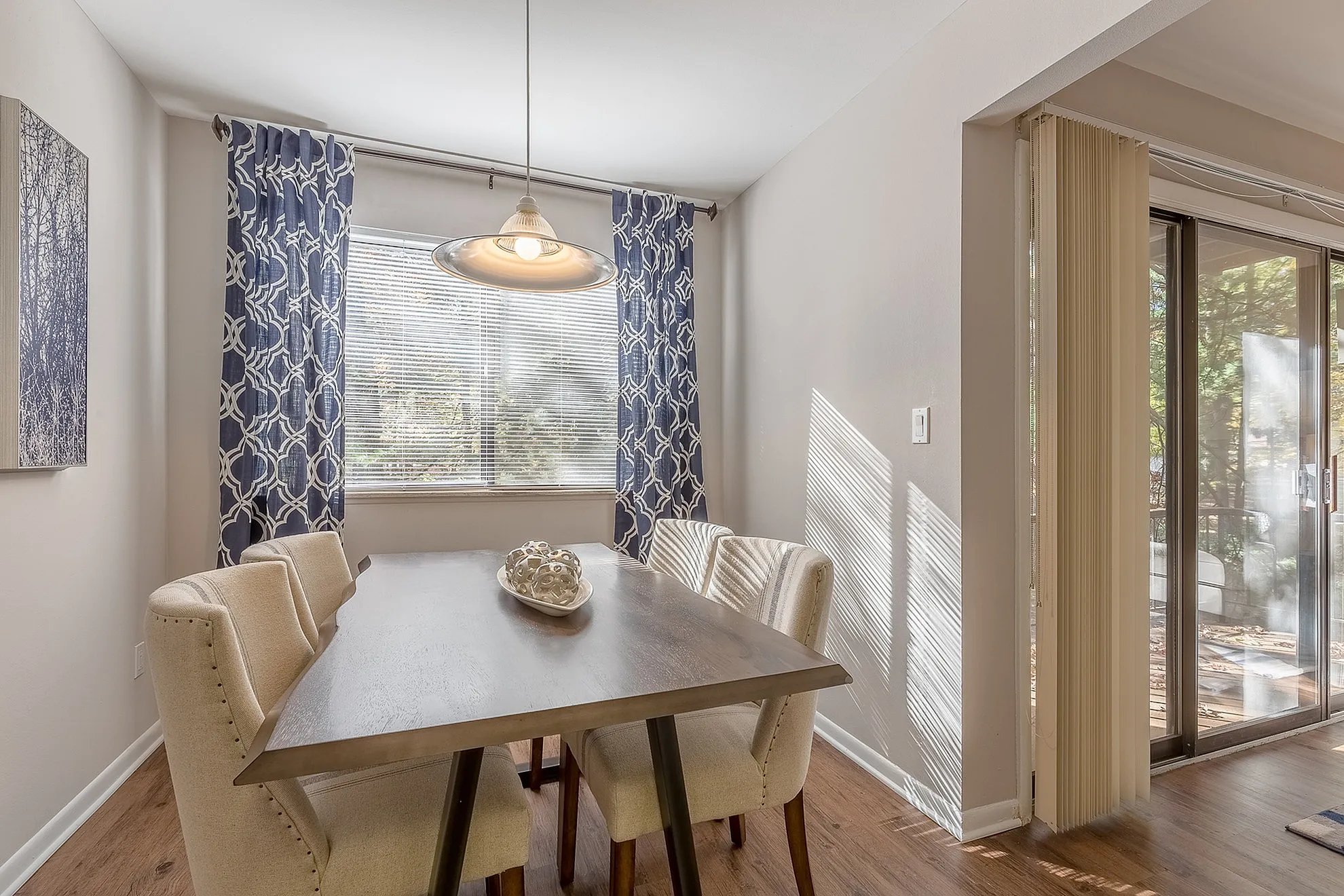 Bright dining area with elegant blue curtains, modern light fixture, and patio access through sliding doors.