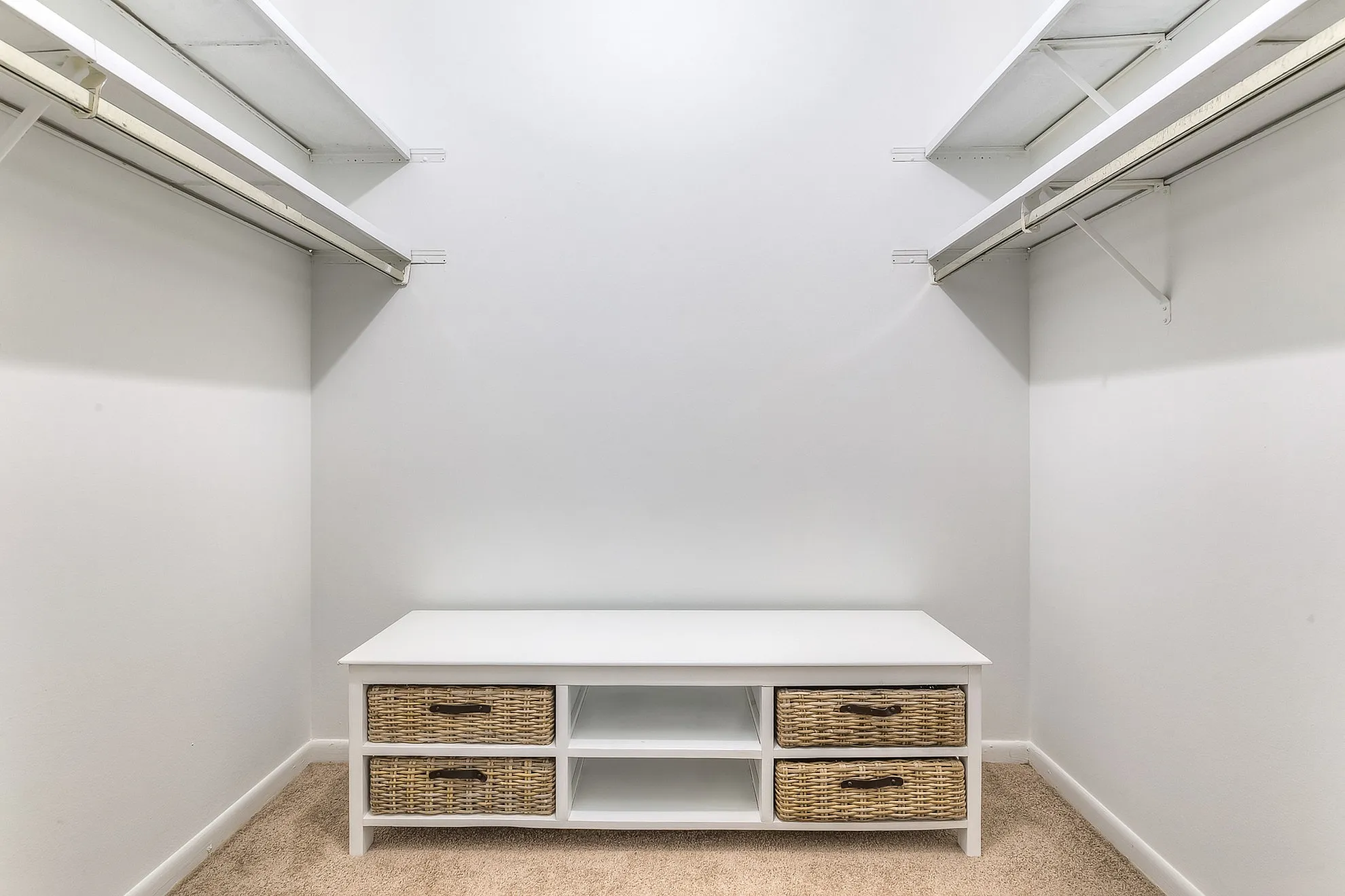 Spacious walk-in closet with ample shelving and stylish wicker storage drawers, offering a perfect blend of practicality and elegance.