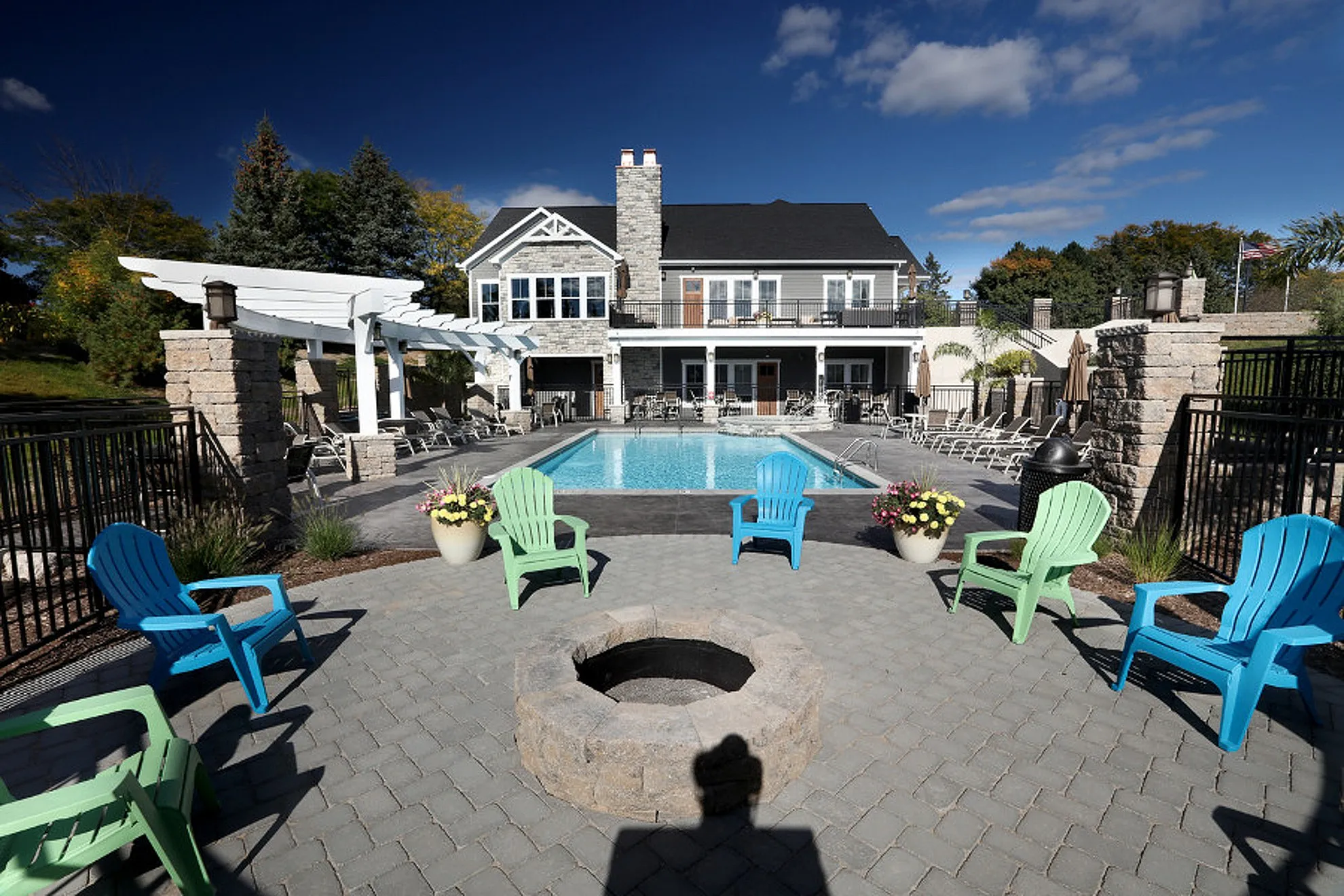 Charming outdoor pool area with colorful chairs and fire pit, perfect for relaxation and gatherings at a modern residence.