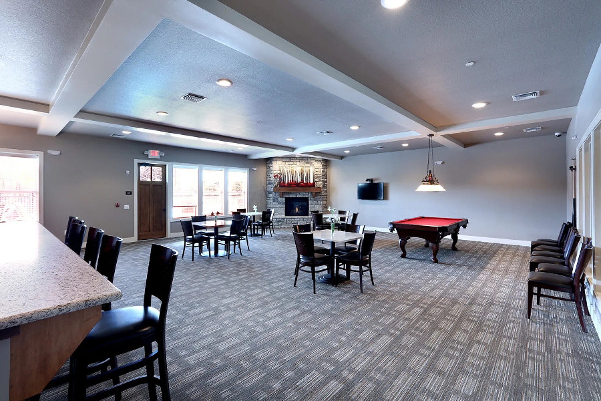 Spacious community lounge with modern decor, featuring a pool table, multiple seating areas, and a cozy fireplace.