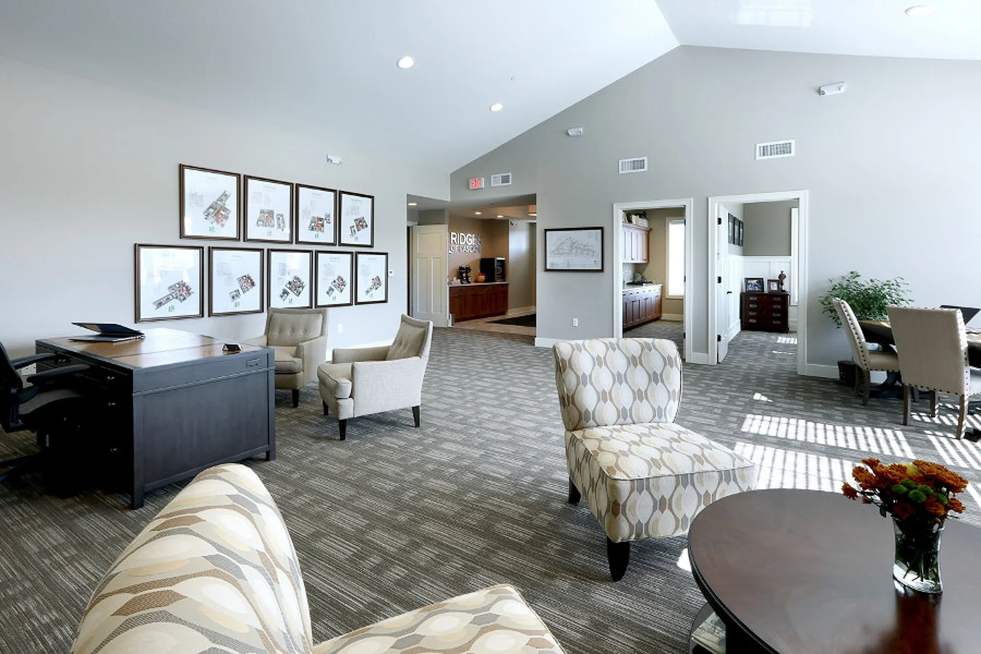 Elegant community lounge with stylish armchairs, sleek wooden desk, and natural light enhancing the open space.