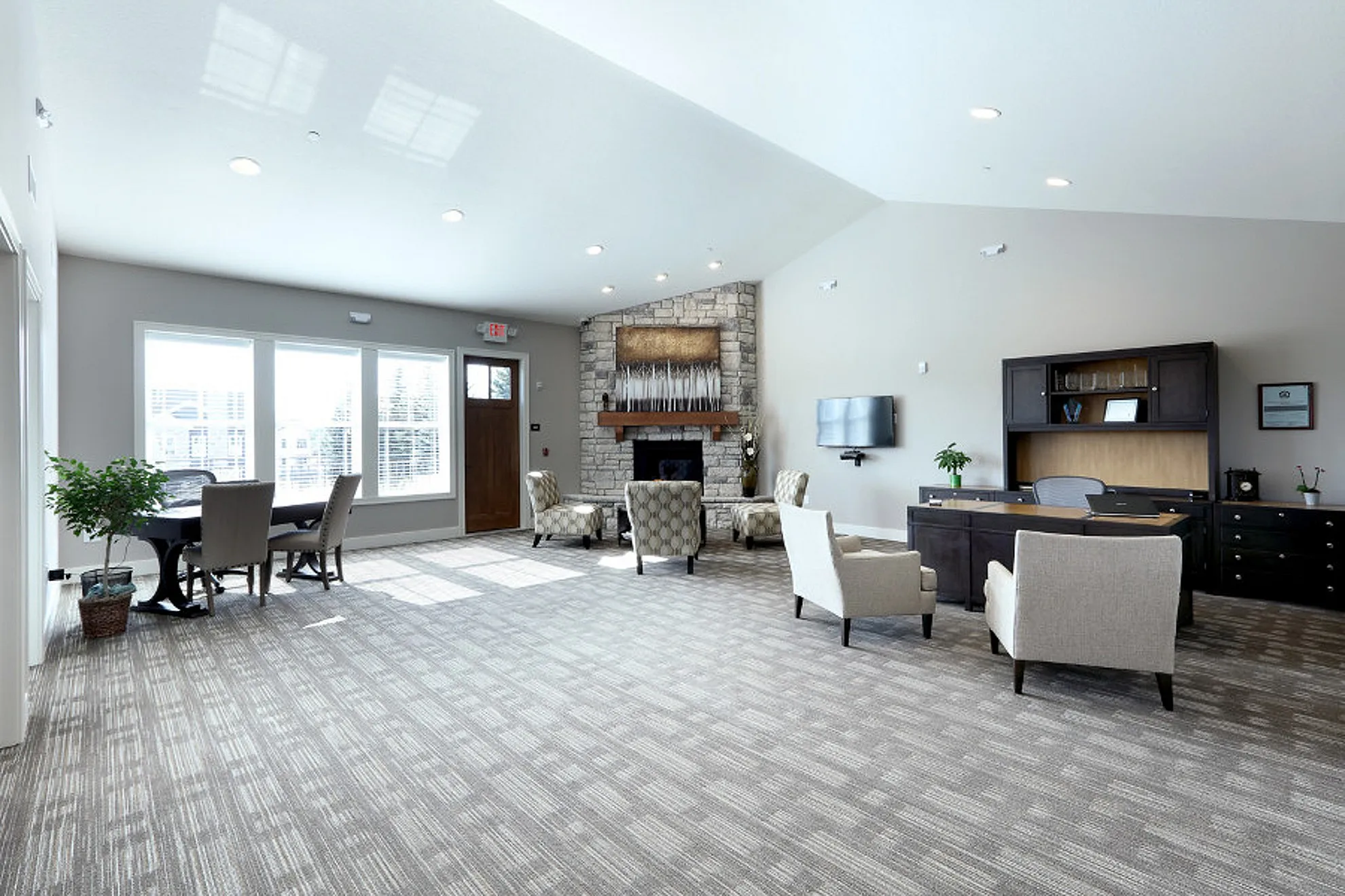Inviting and spacious living area with large windows, a stone fireplace, and elegant seating, perfect for comfortable gatherings.