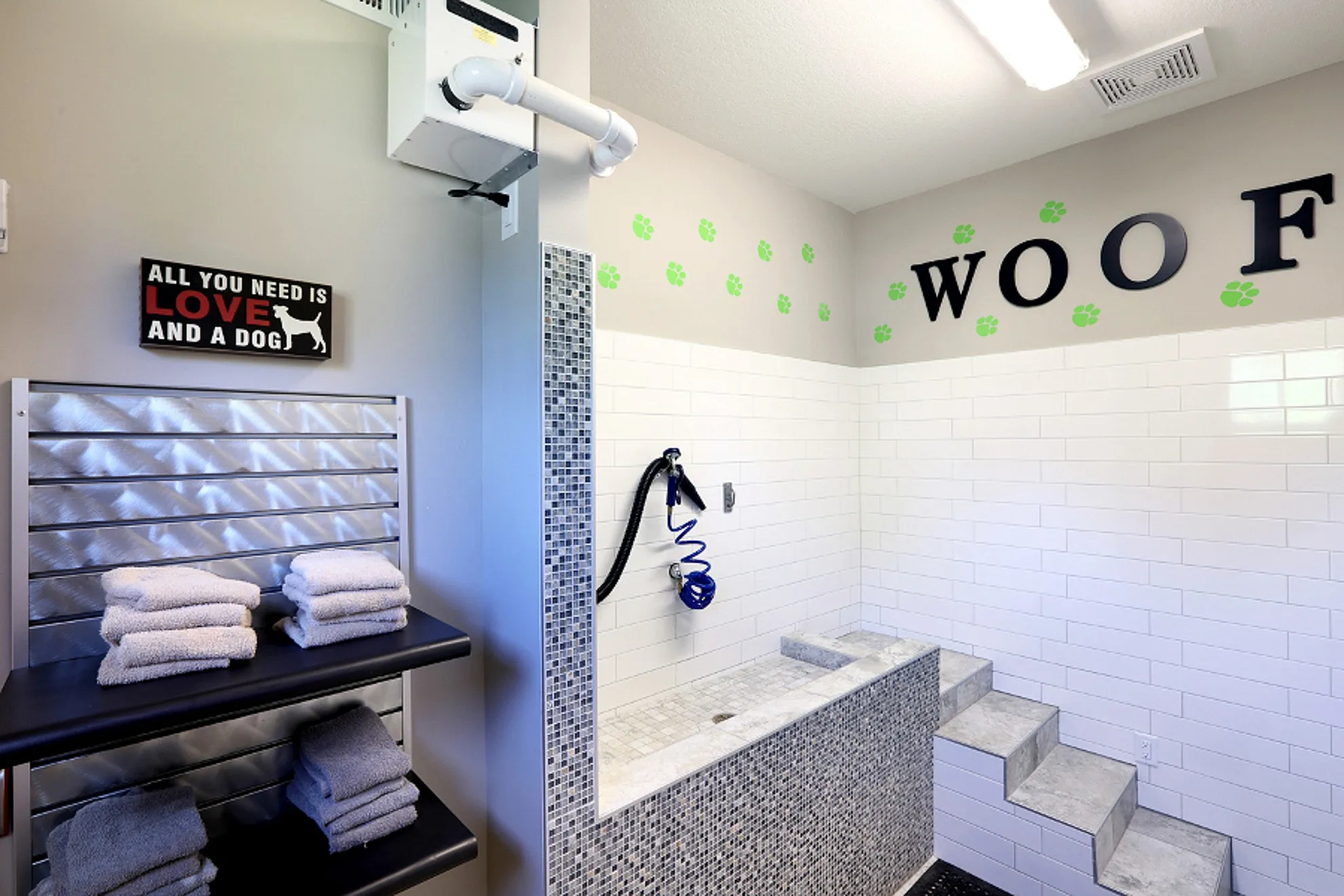 Modern pet grooming station with tiled walls, built-in bathtub, and decorative paw prints for a stylish and convenient dog wash area.