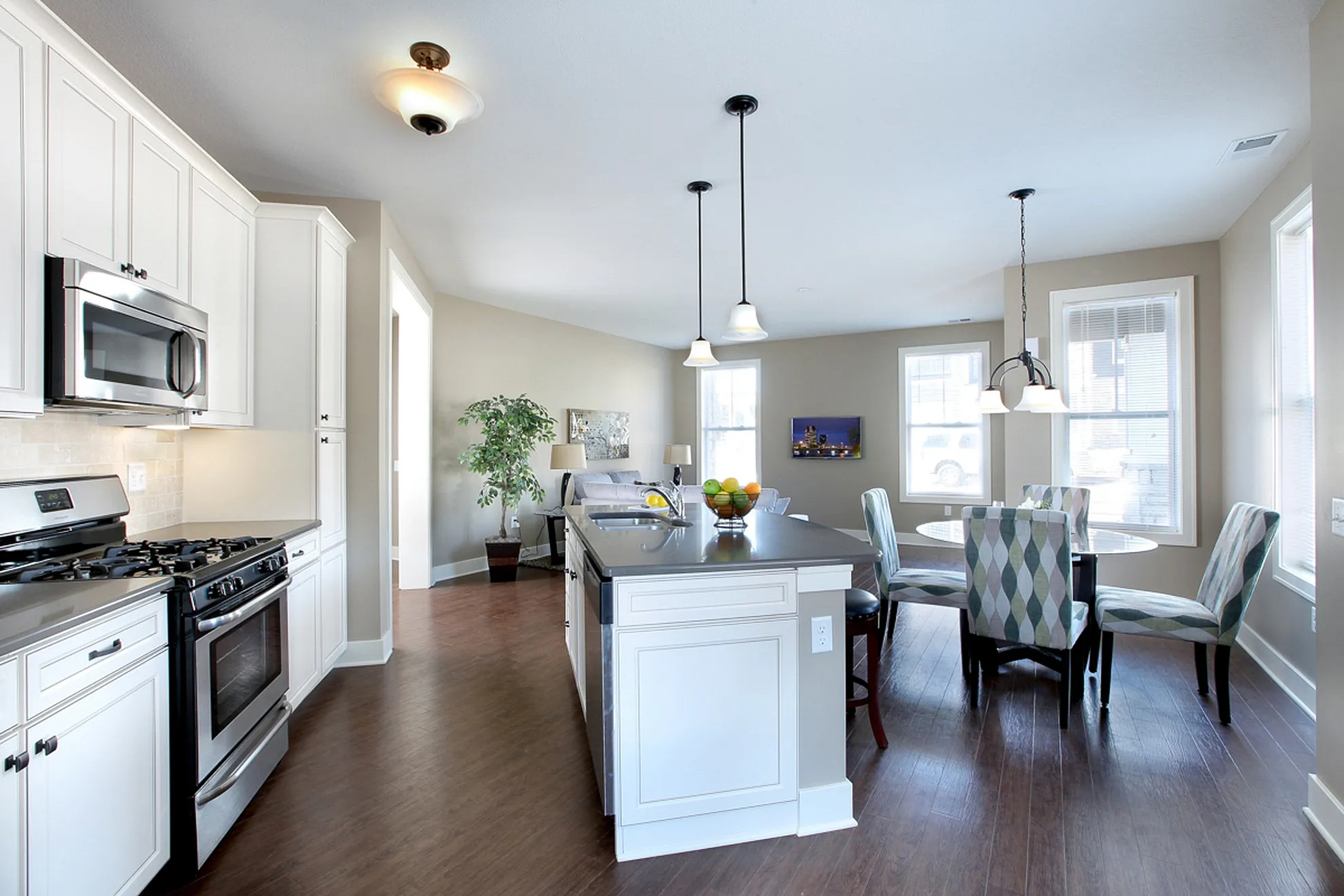 Modern open-concept kitchen and dining area with elegant lighting, featuring sleek stainless steel appliances and stylish countertops.