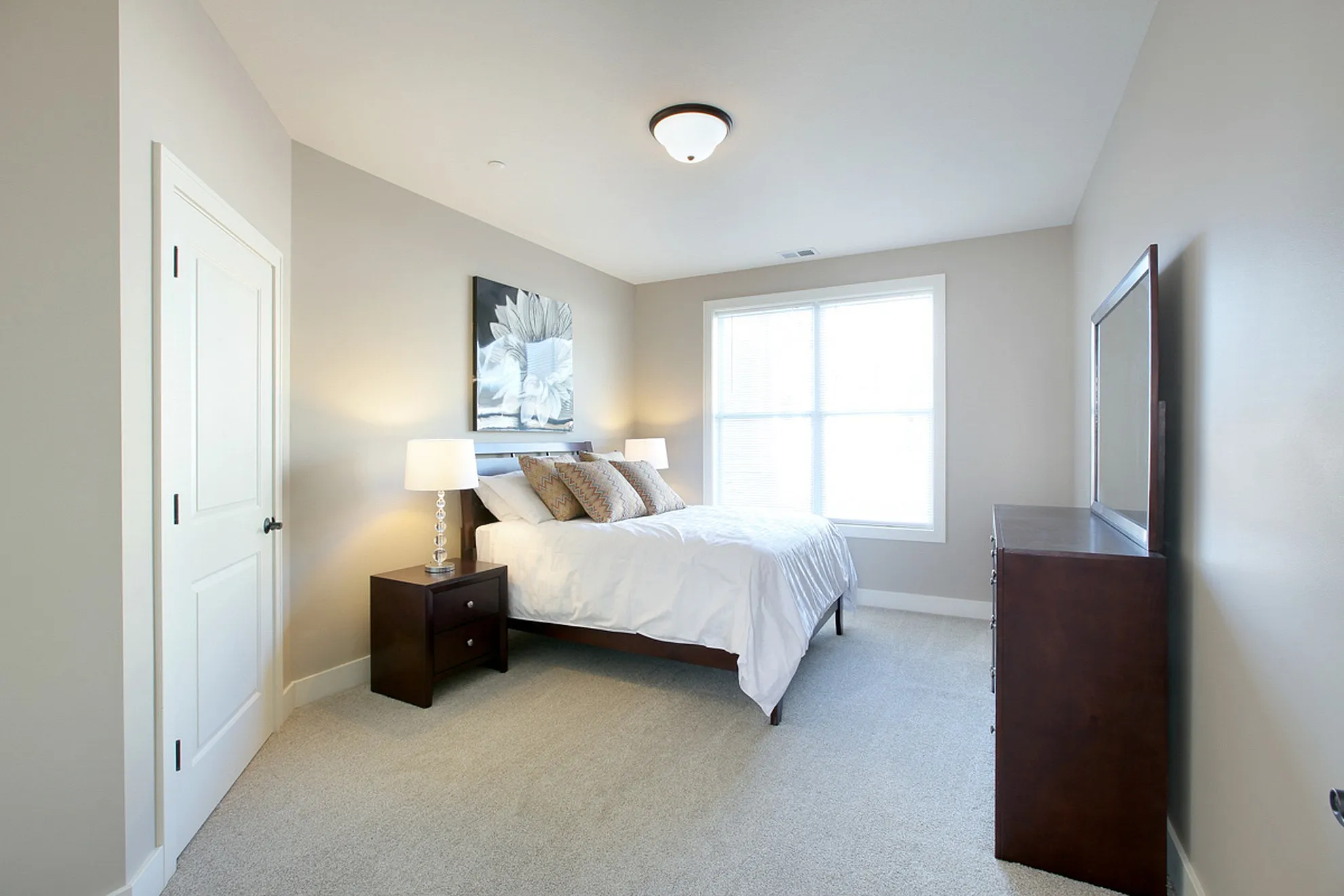 Inviting bedroom with natural light, neutral tones, and elegant decor featuring plush bedding and stylish furniture.