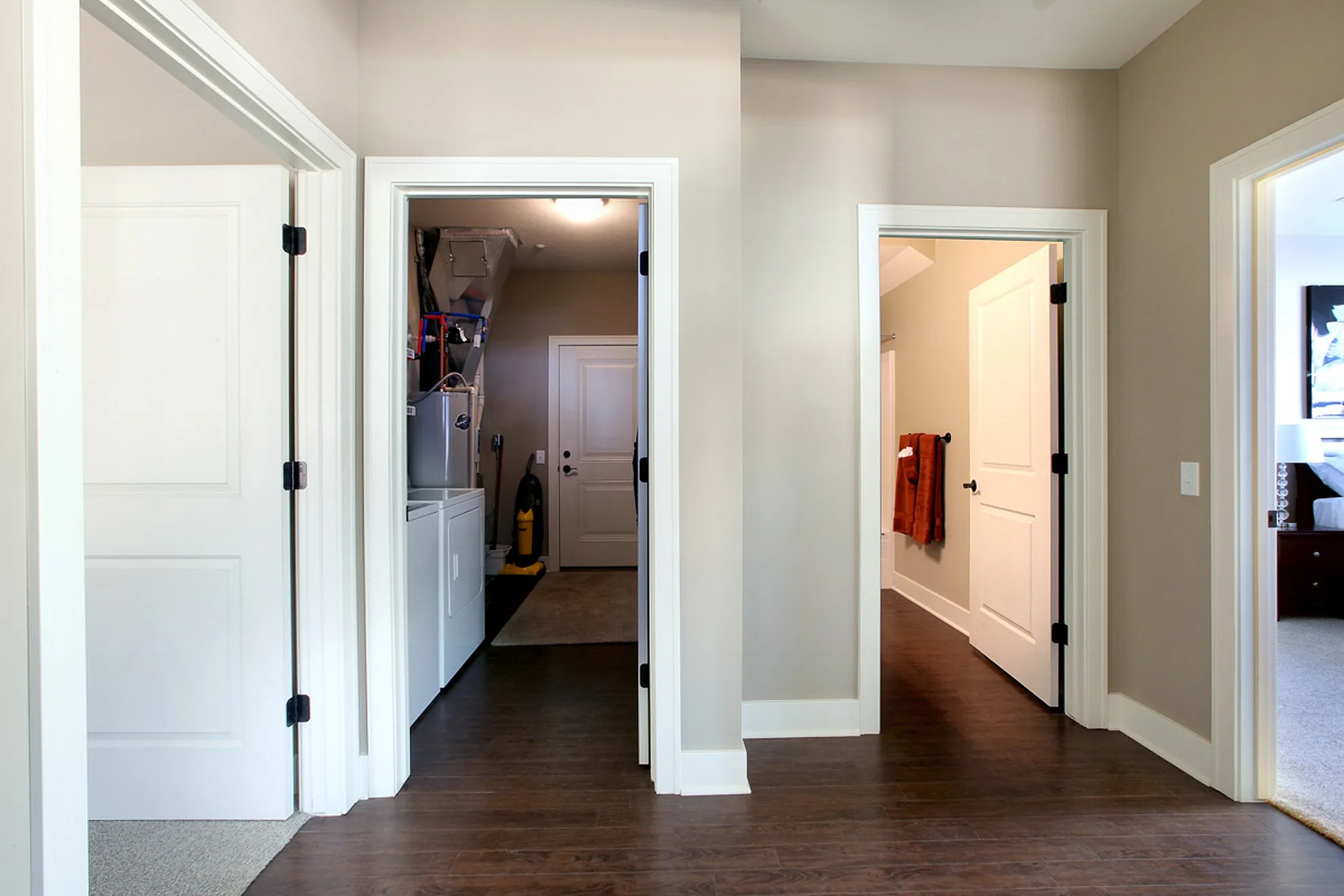 Bright hallway with elegant wooden flooring, leading to multiple rooms, including a modern laundry area with sleek appliances.