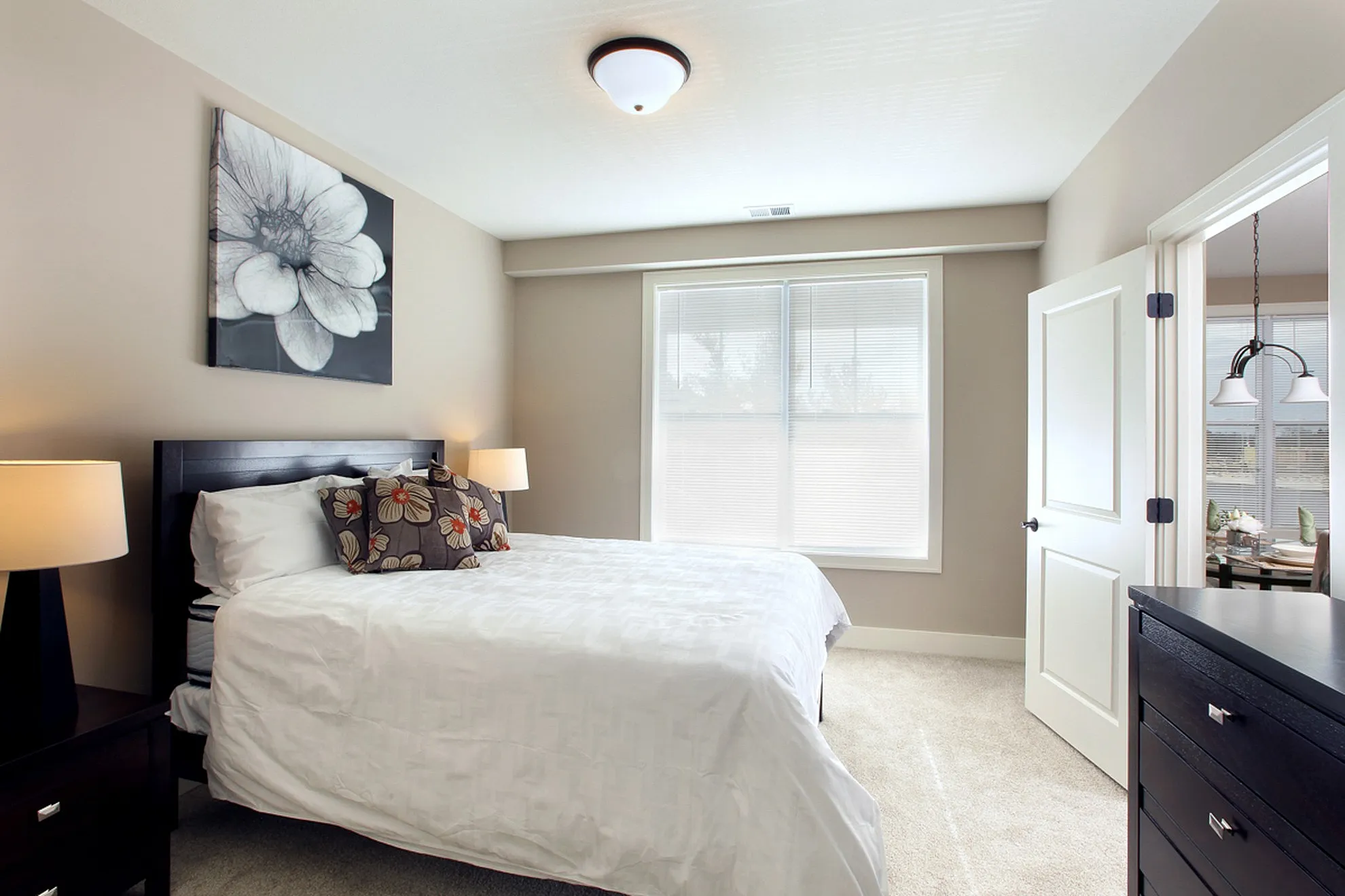 Bright and inviting bedroom featuring cozy bedding, stylish floral decor, and abundant natural light.