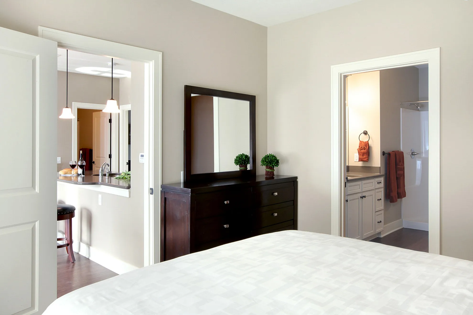 Inviting apartment interior showcasing a stylish bedroom, sleek en-suite bathroom, and a modern kitchen with a breakfast bar.