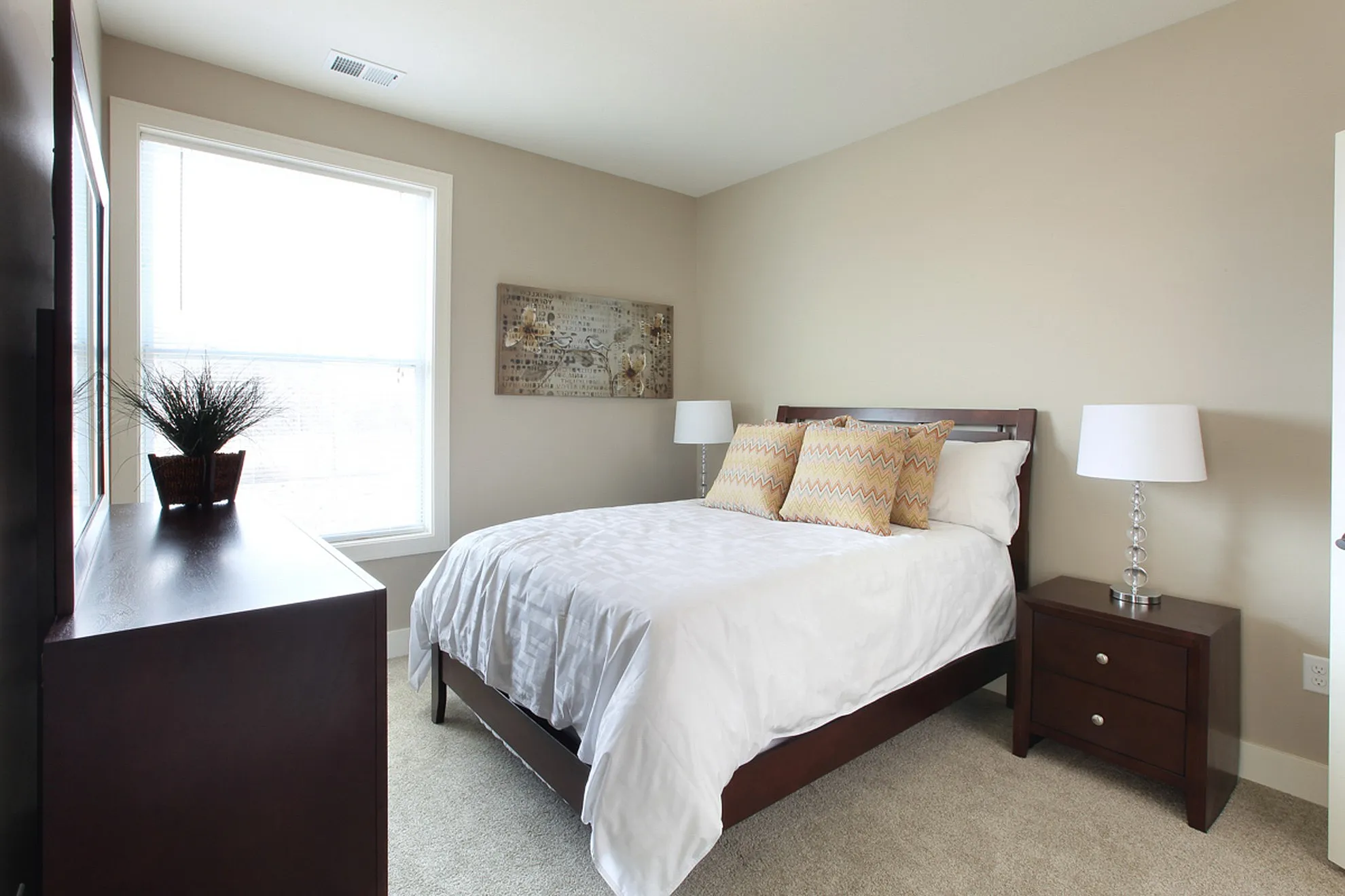 Inviting bedroom with natural light, featuring a cozy bed with plush pillows, elegant bedside tables, and modern decor.