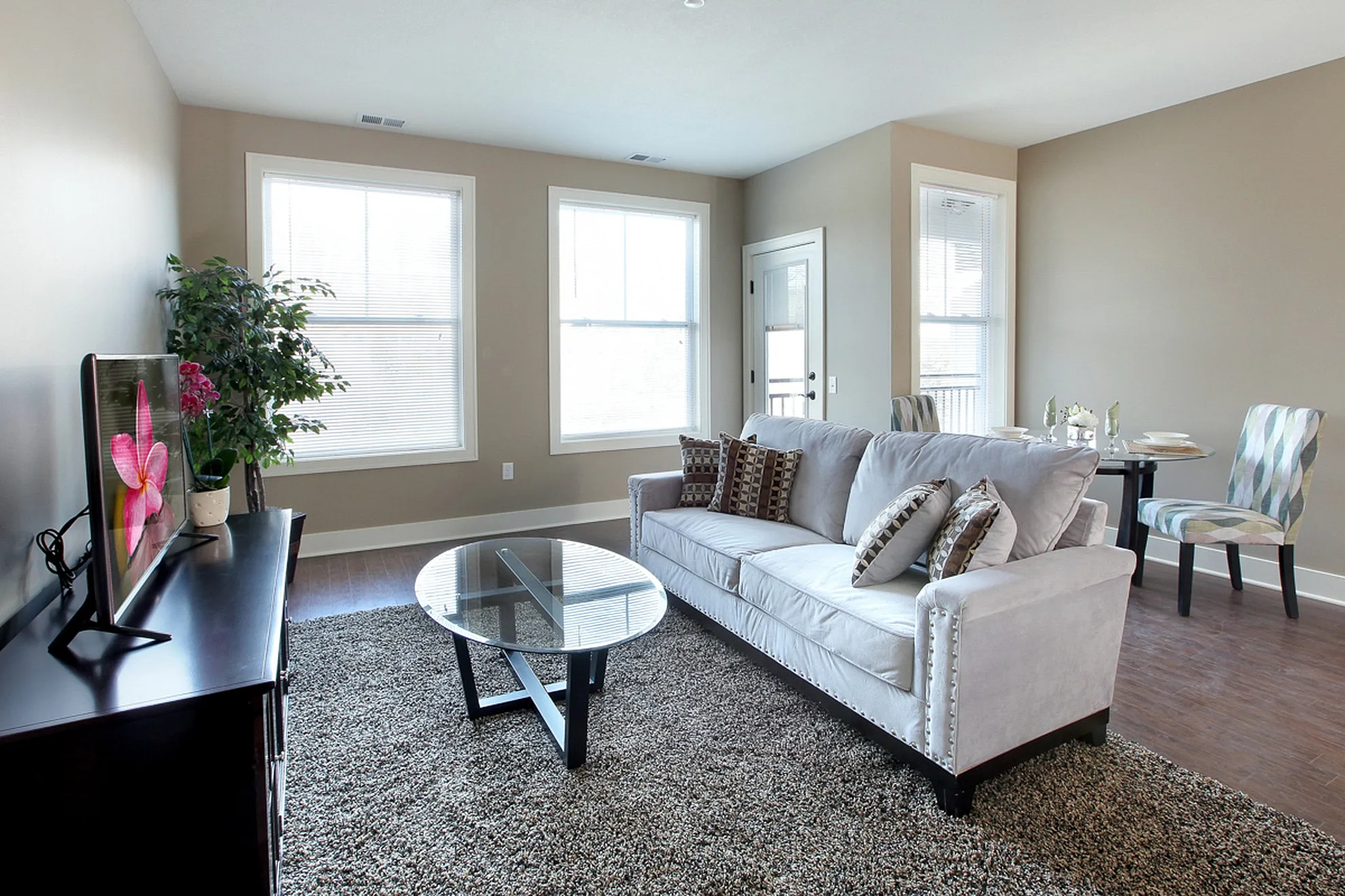 Bright and inviting living room with plush sofa, modern decor, and abundant natural light, featuring a cozy dining area.